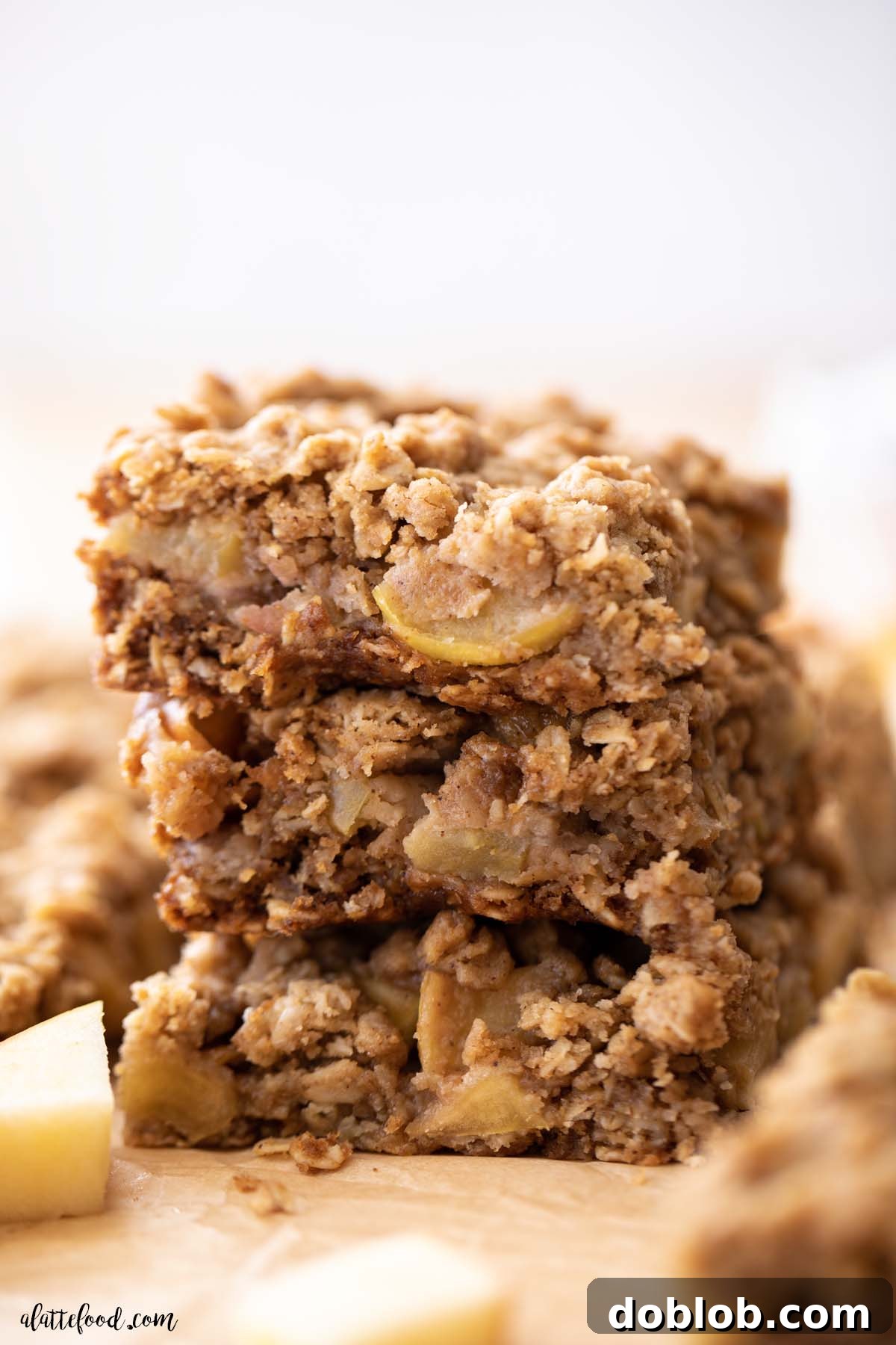 stack of three apple crumb bars on brown parchment paper.