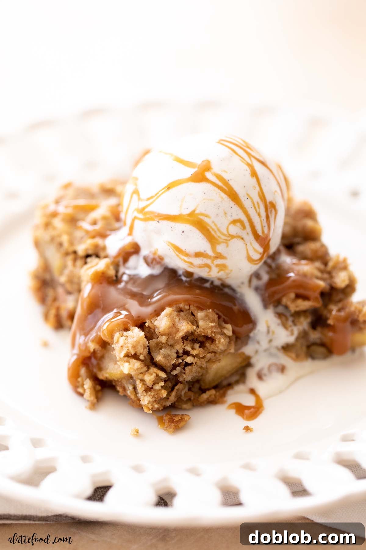 salted caramel apple crumb bar with ice cream and extra caramel drizzle on a white plate.