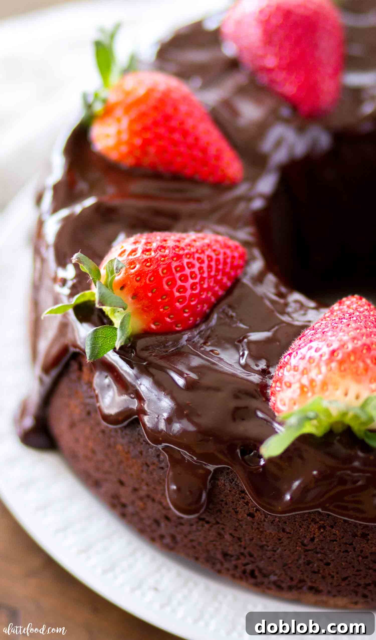 A moist and rich chocolate pound cake, made from scratch with sour cream and melted chocolate, topped with luxurious chocolate ganache. Enjoy it plain or with ice cream or whipped cream for a heavenly treat! A stunning whole chocolate pound cake generously coated with chocolate ganache and adorned with bright red fresh strawberries, inviting a delectable slice.