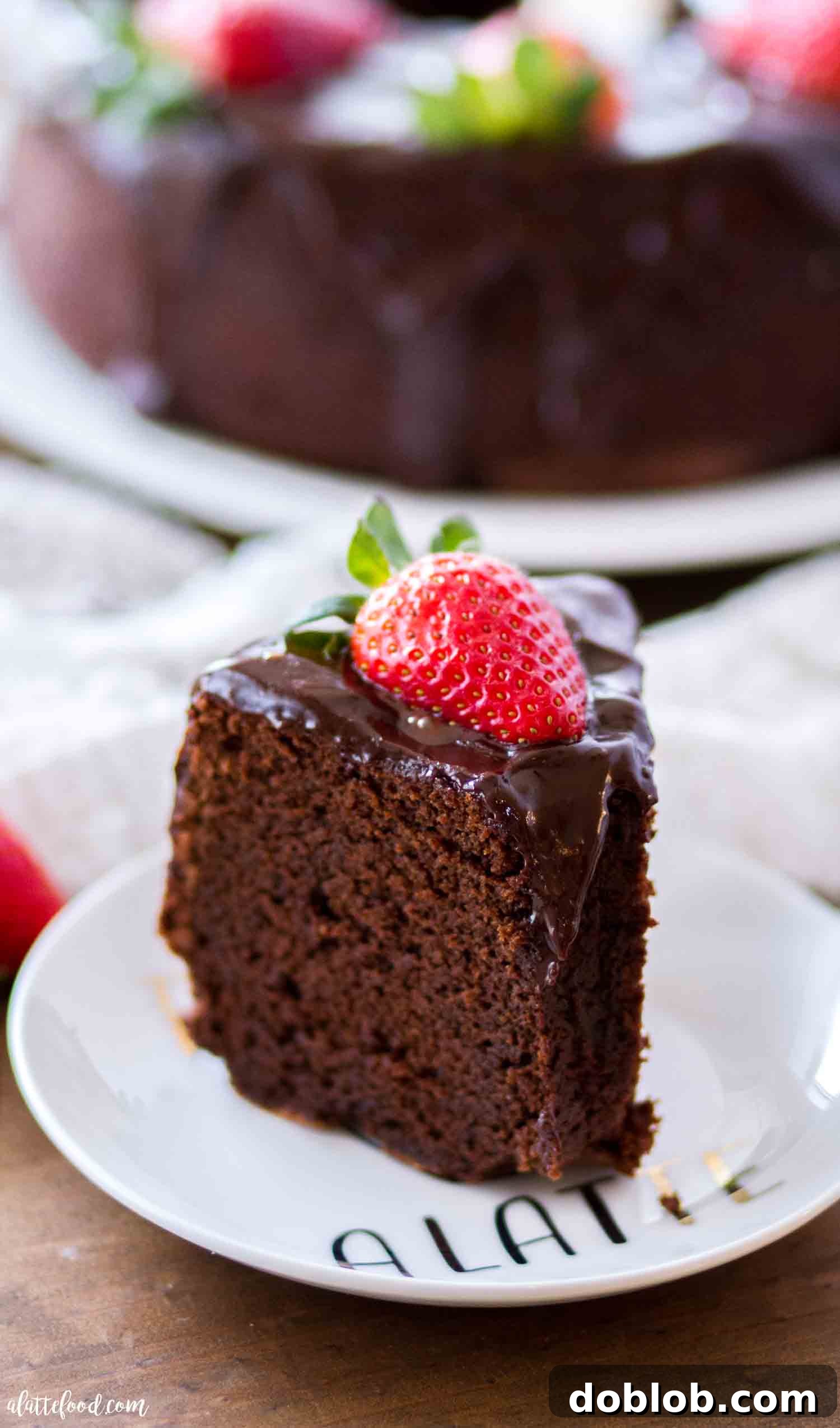 This Southern chocolate pound cake recipe, made with sour cream and melted chocolate, results in a rich, fudgy, and moist chocolate bundt cake, perfectly finished with a luscious ganache. An easy baking favorite! A single slice of chocolate pound cake with a smooth ganache topping resting on a small white plate, highlighting its rich color and inviting texture.
