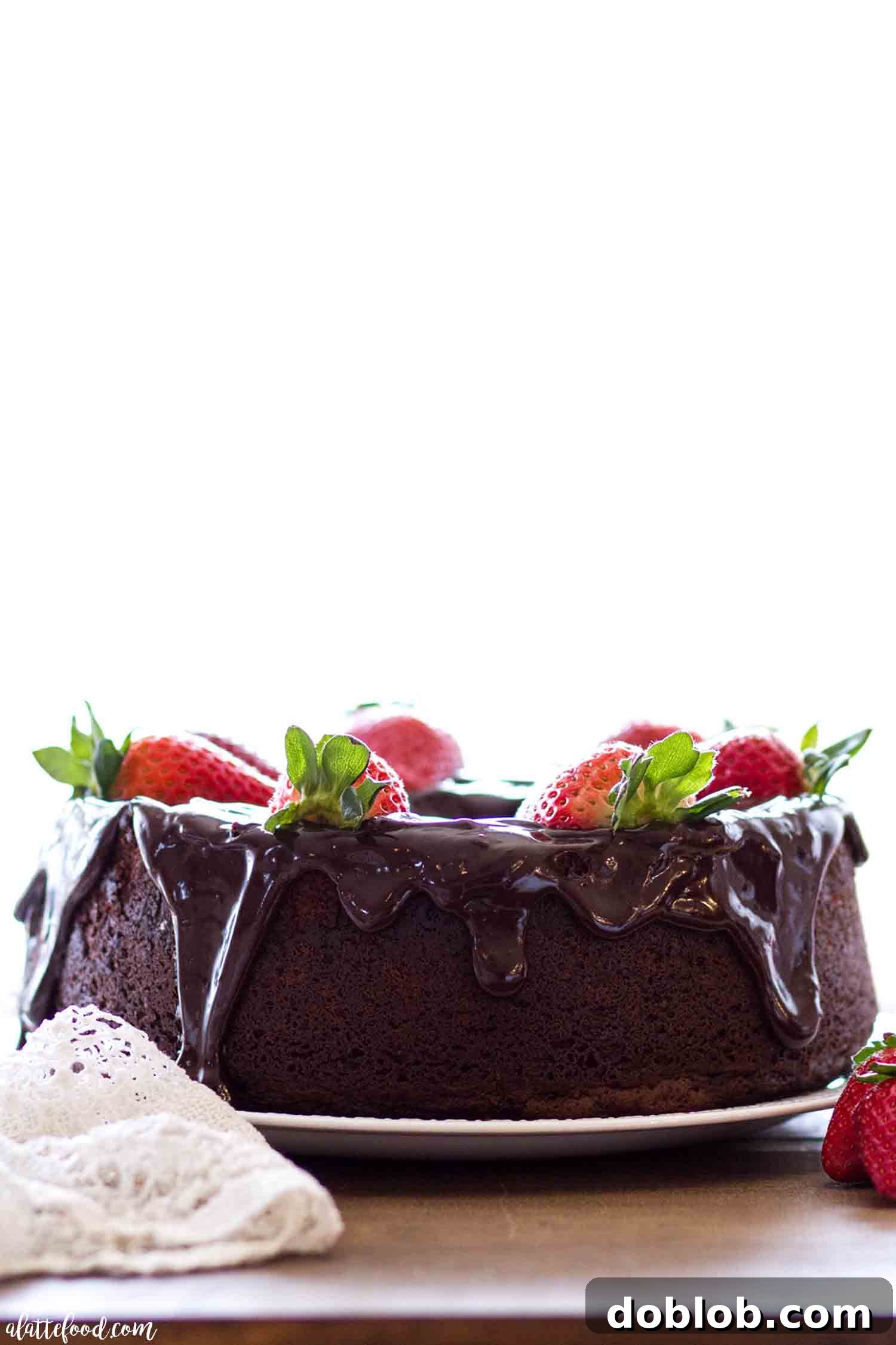 The secret to this rich and fudgy chocolate pound cake? It’s made with melted chocolate, not cocoa powder, for an unparalleled taste! A baked chocolate pound cake, elegantly drizzled with ganache, displayed on a rustic wooden cutting board, highlighting its appealing texture.