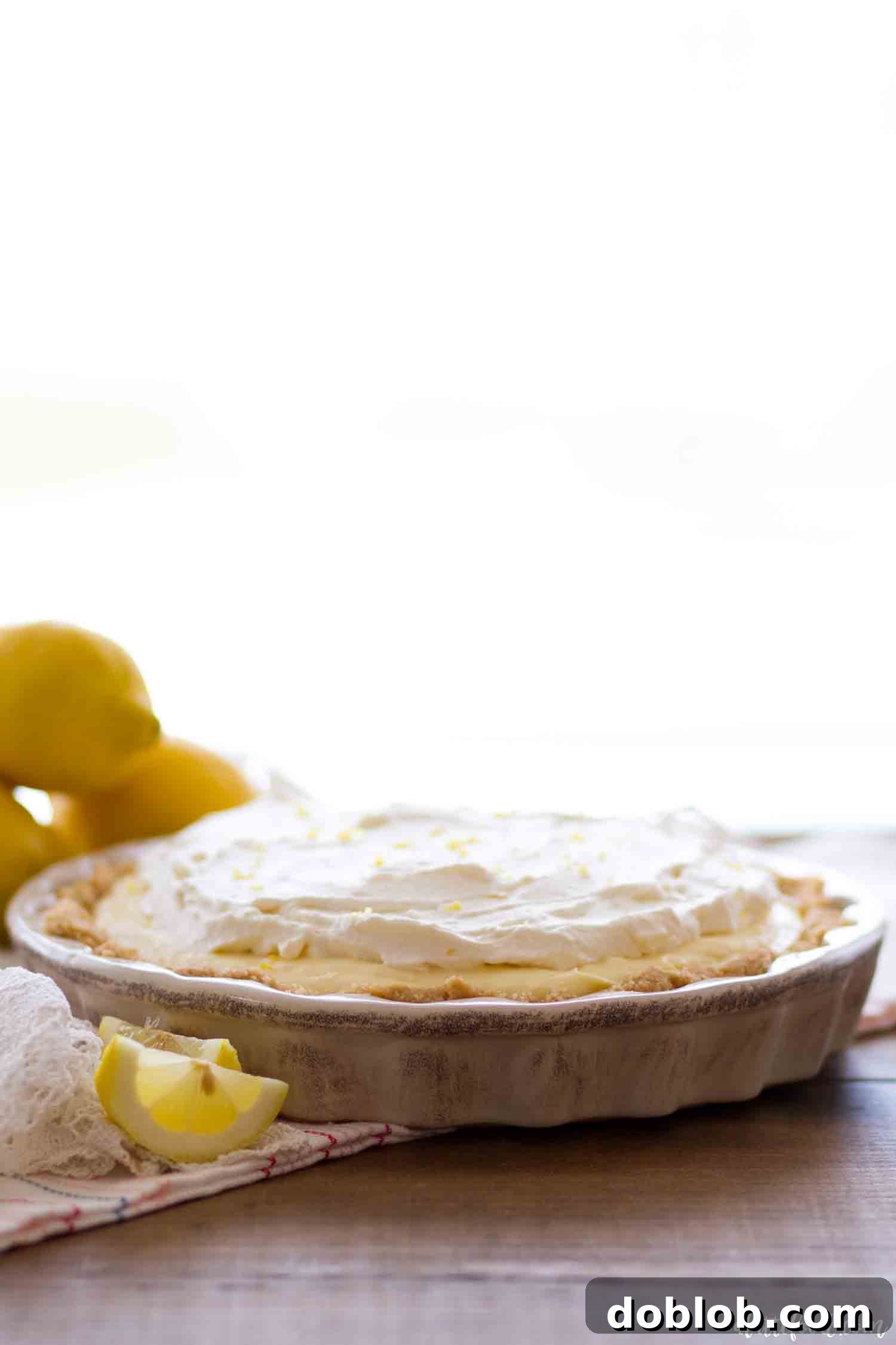 No-Bake Lemon Cream Pie with Lemon Whipped Cream and Vanilla Wafer Crust. An entire No-Bake Lemon Cream Pie, generously topped with lemon whipped cream and a sprinkle of lemon zest, served in a classic vanilla wafer crust.