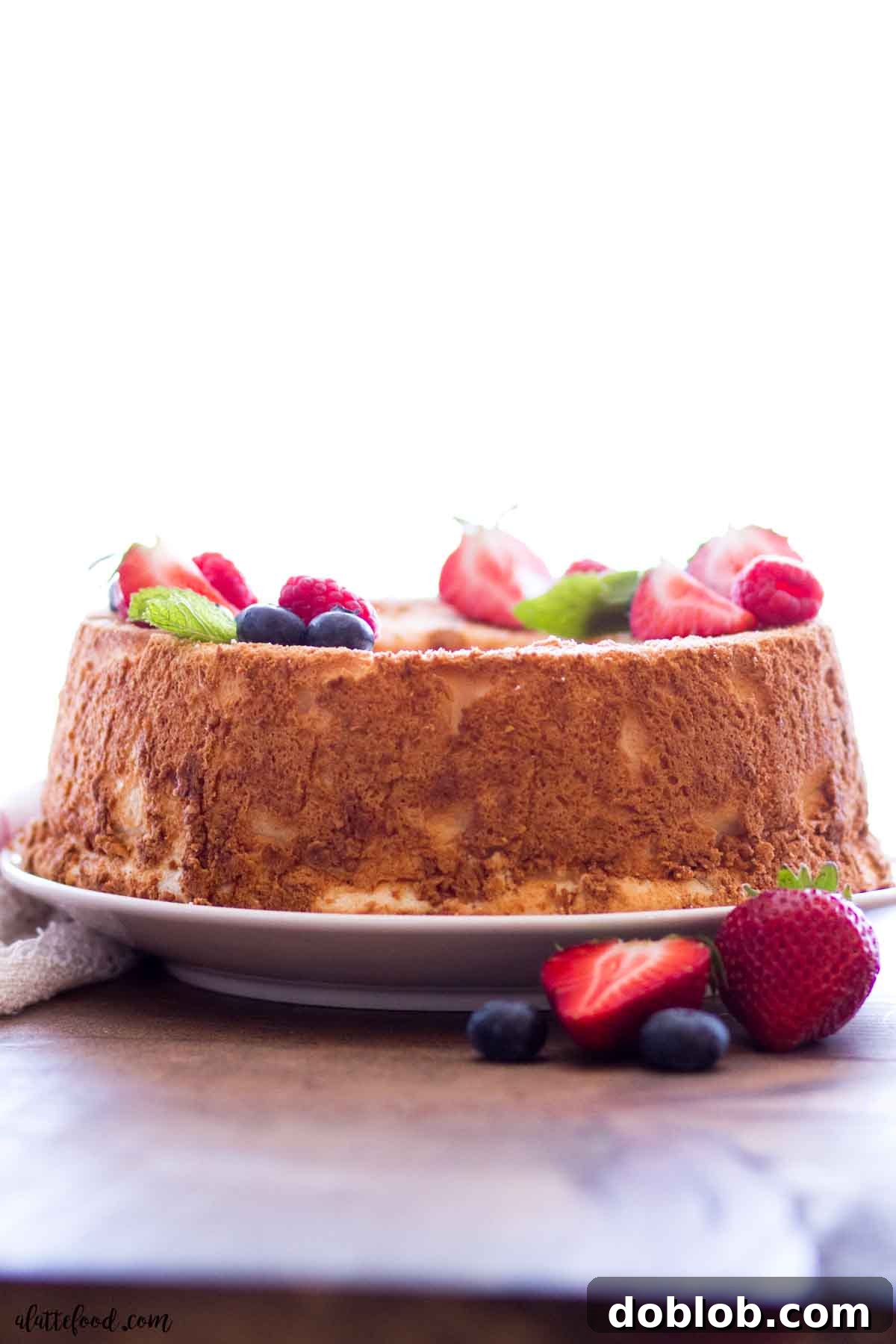 baked angel food cake with fresh berries on white plate.
