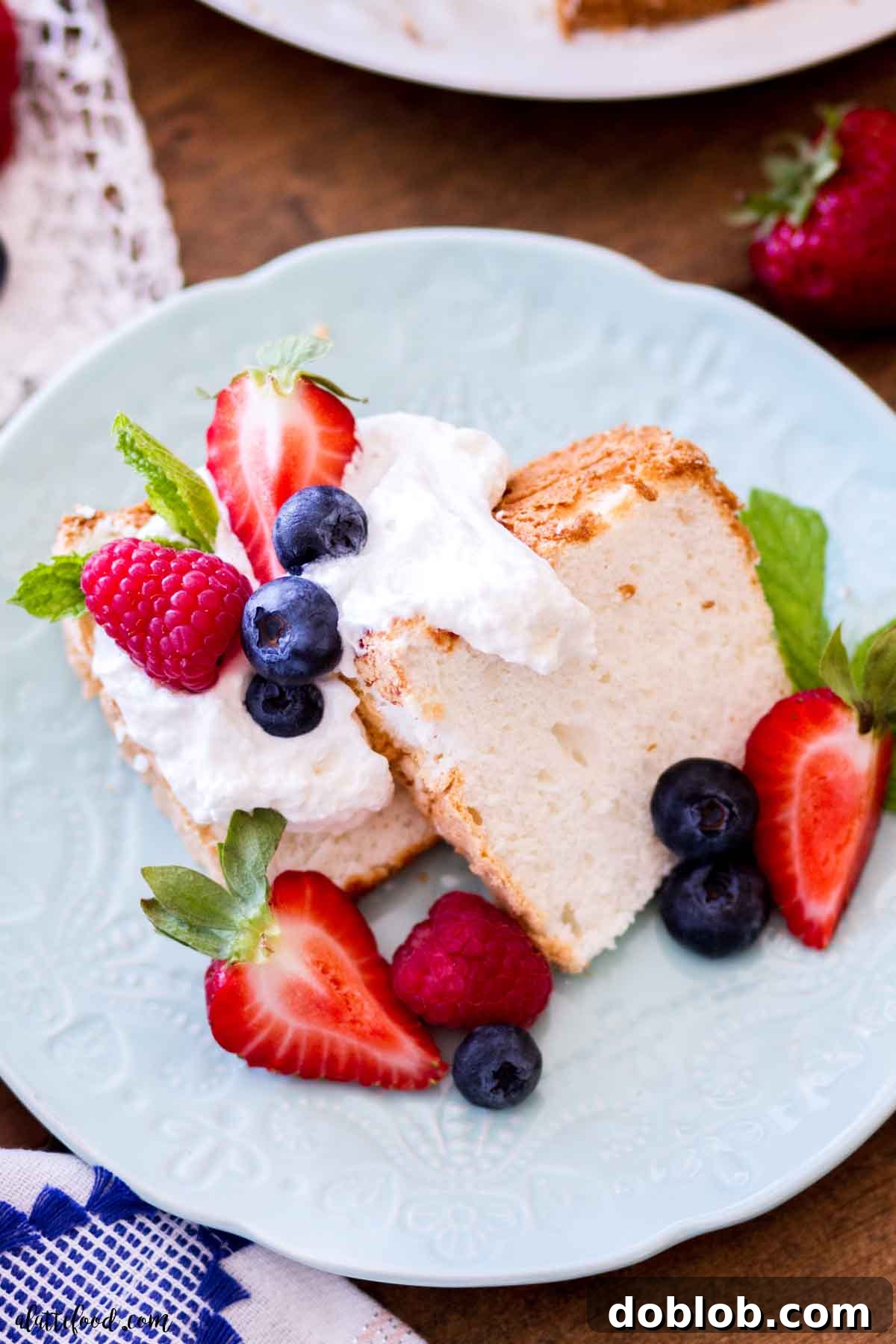 angel food cake slice with fresh berries and mint on blue plate.