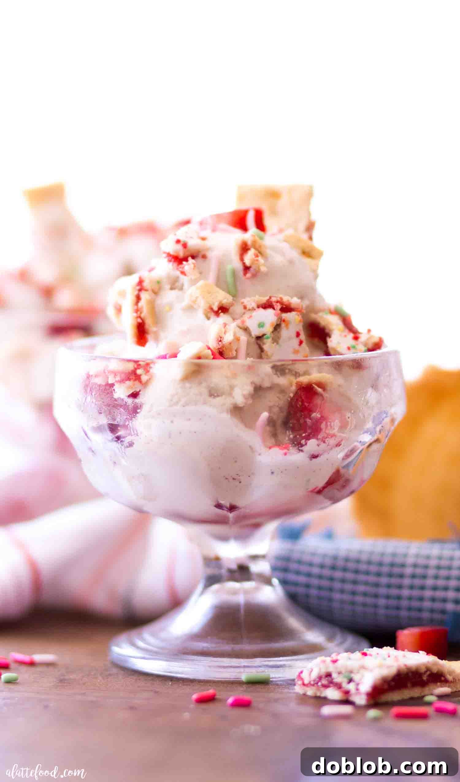 Four Deliciously Easy Ice Cream Sundae Recipes 5 A beautiful Vanilla Strawberry Pop Tart Ice Cream Sundae, generously garnished with fresh strawberries, colorful sprinkles, and pieces of Pop Tart, served elegantly in a clear glass dish