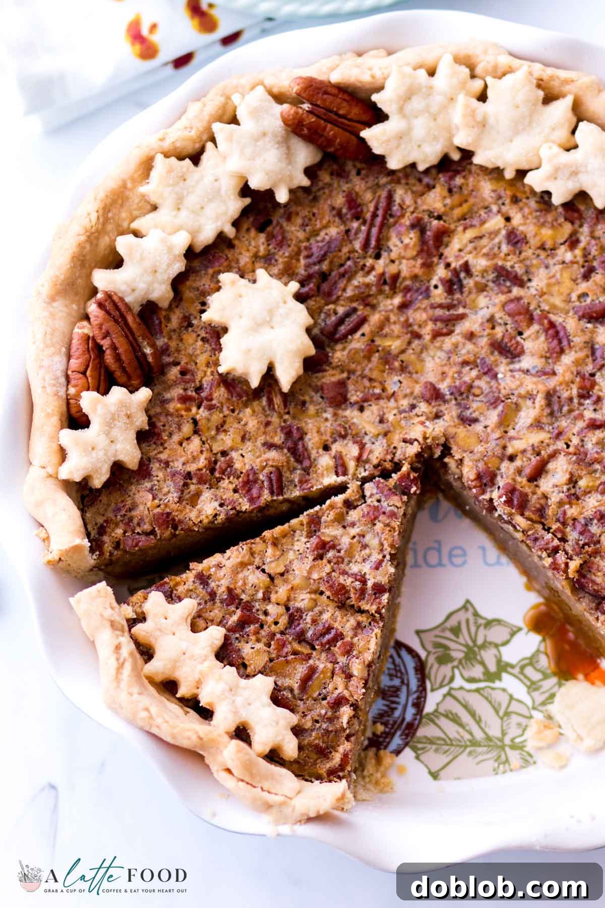 An inviting slice of Butterscotch Pecan Pie rests in a pristine white pie plate, showcasing its golden crust and rich filling.