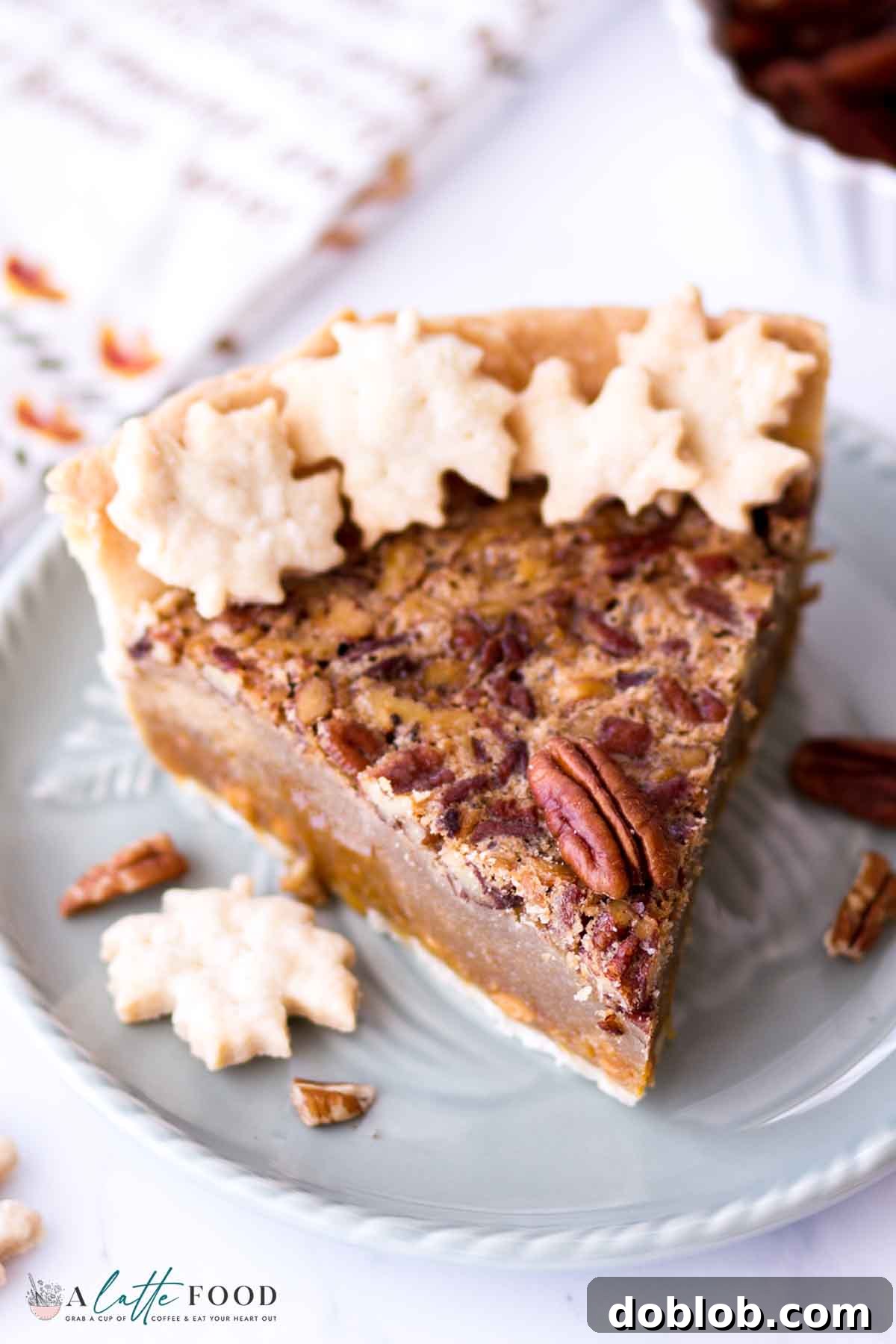 slice of butterscotch pecan pie with toasted pecans on top on a teal plate.