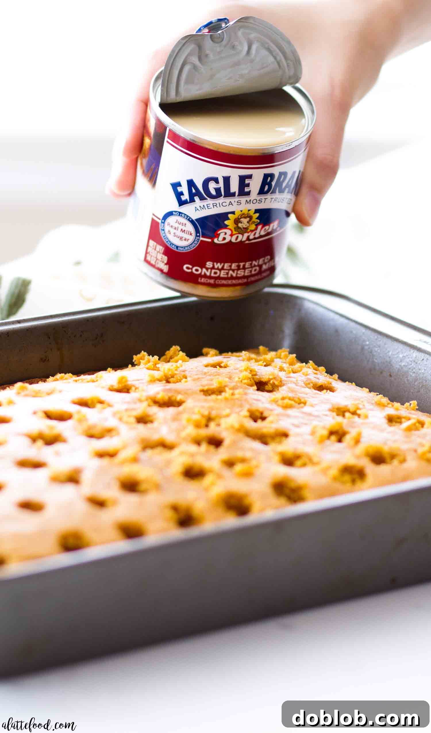 A whole Pumpkin Pie Poke Cake in a baking dish, generously topped with a homemade pumpkin cream filling and a cloud-like cream cheese whipped frosting, ready to be served.
