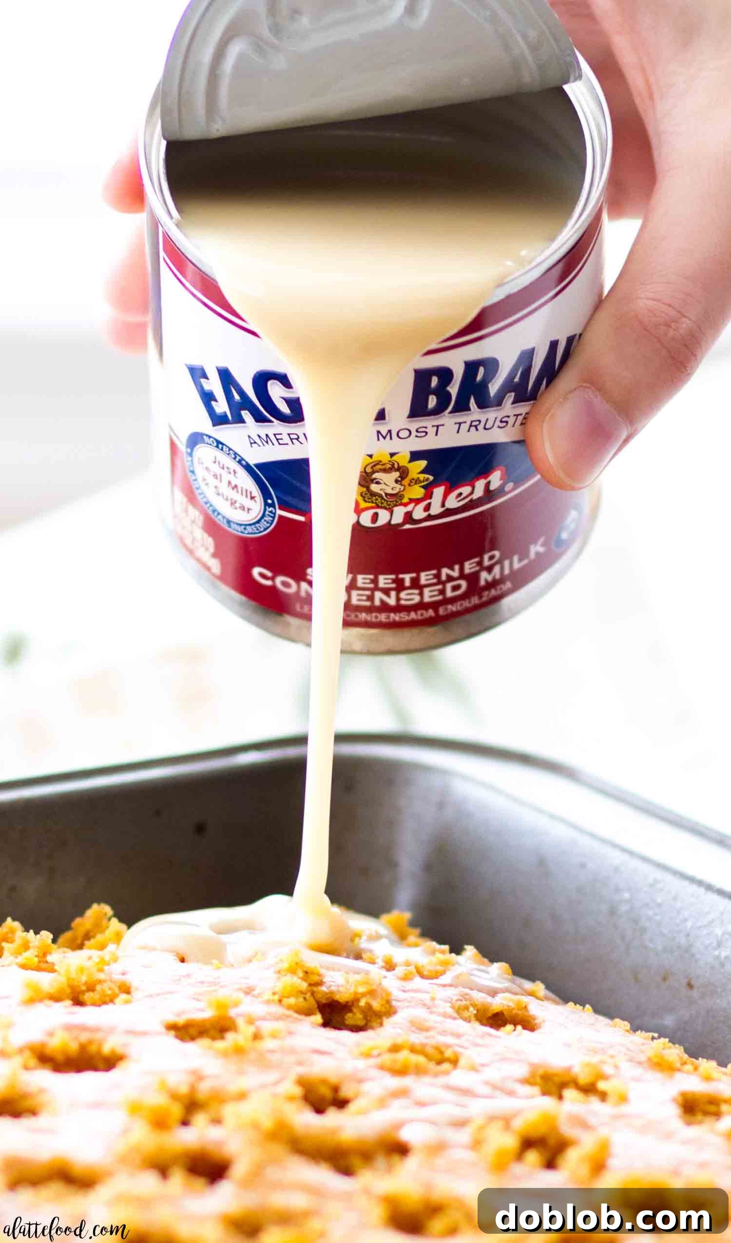 A close-up of the easy pumpkin poke cake revealing the luscious pumpkin cream pie filling beneath the whipped cream cheese frosting, topped with crunchy pecans.