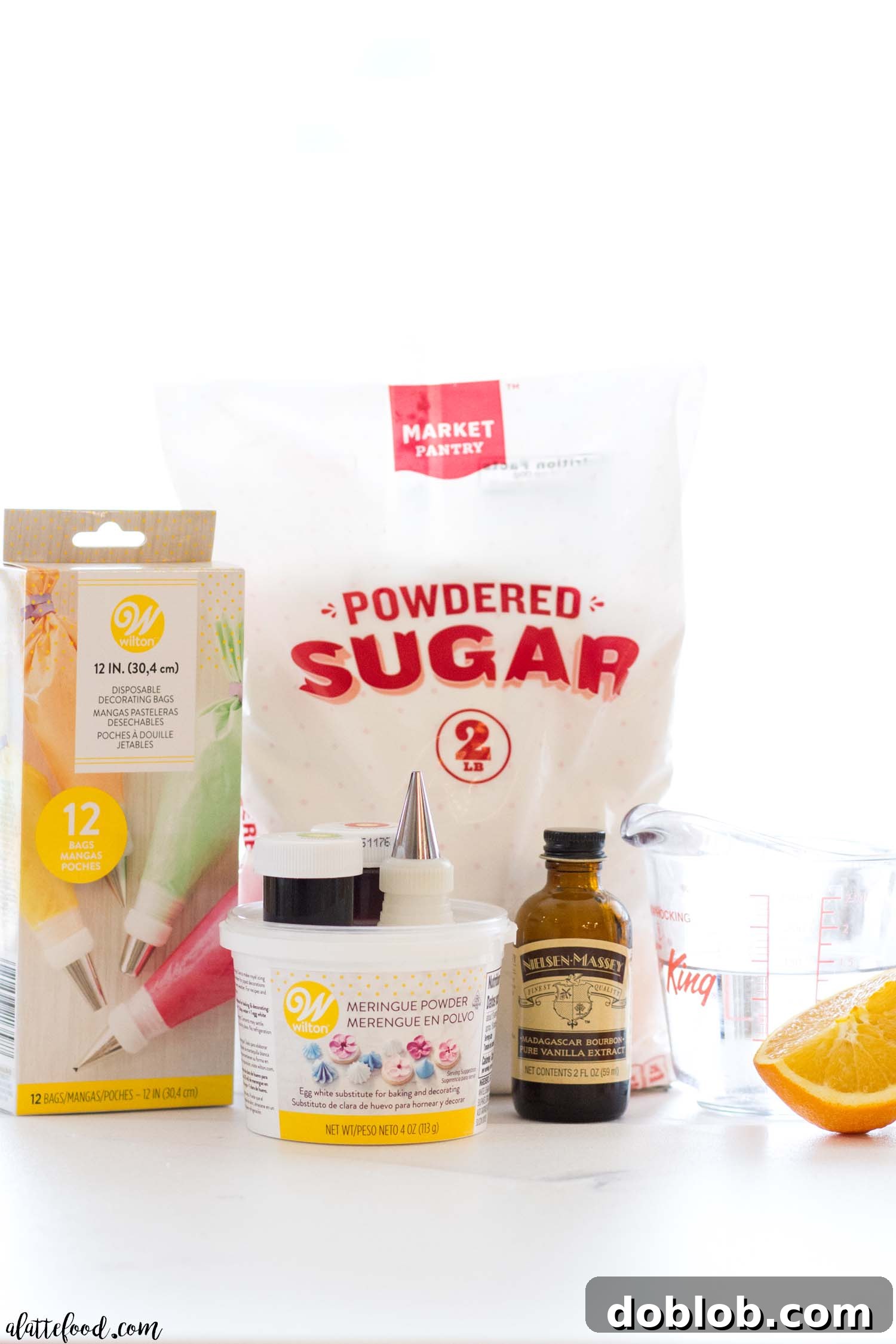 Perfect Royal Icing Made Simple 2 Essential ingredients for homemade royal icing: powdered sugar, meringue powder, water, orange juice, and vanilla extract on a light surface.