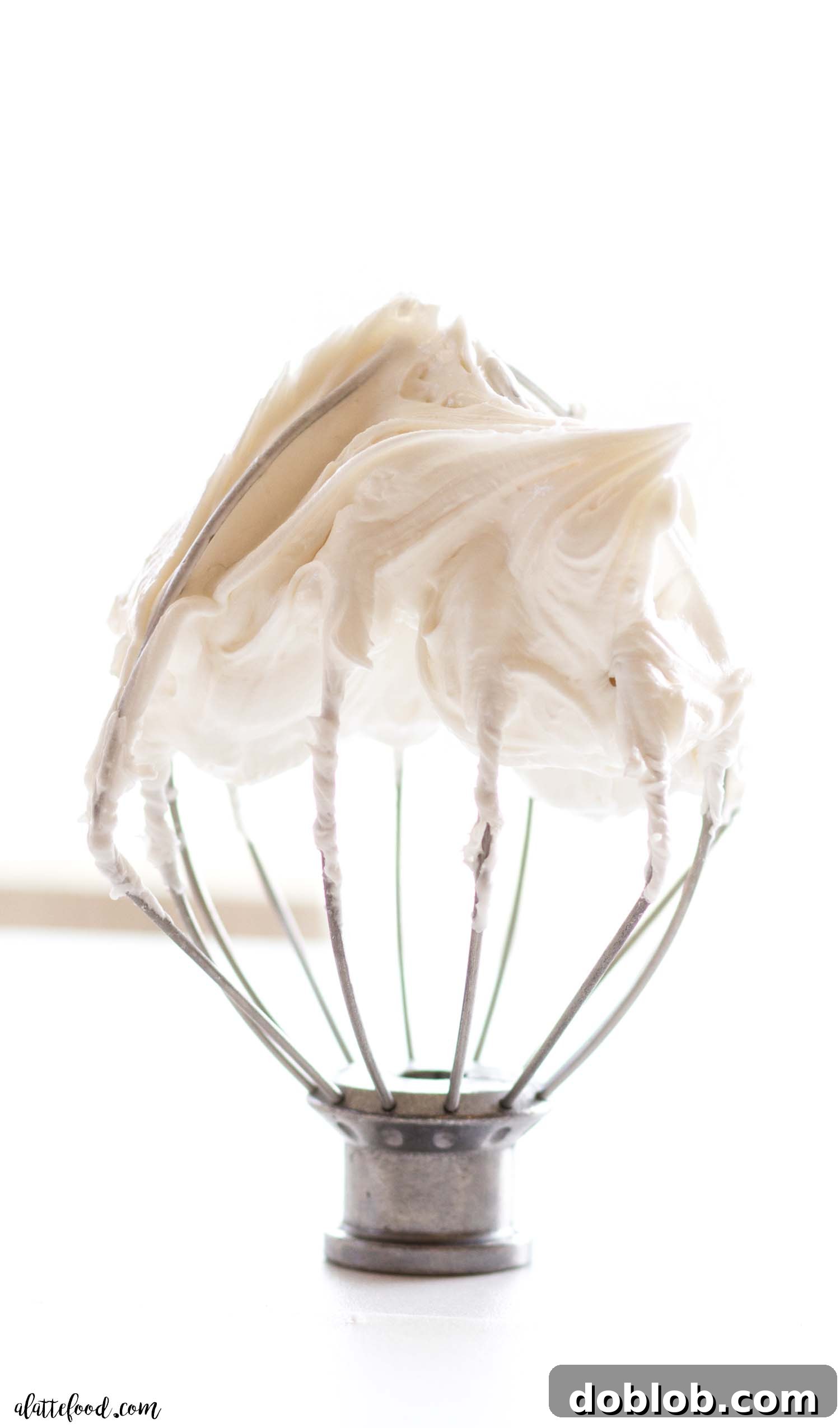 Learn how to make royal icing at home to decorate all of your cookies. This is an easy recipe that uses meringue powder (no egg whites or corn syrup) and other easy ingredients. Learn all the tips and tricks to make royal icing so easy! A whisk attachment coated with stiff piping consistency royal icing, demonstrating its readiness for detailed decorating.