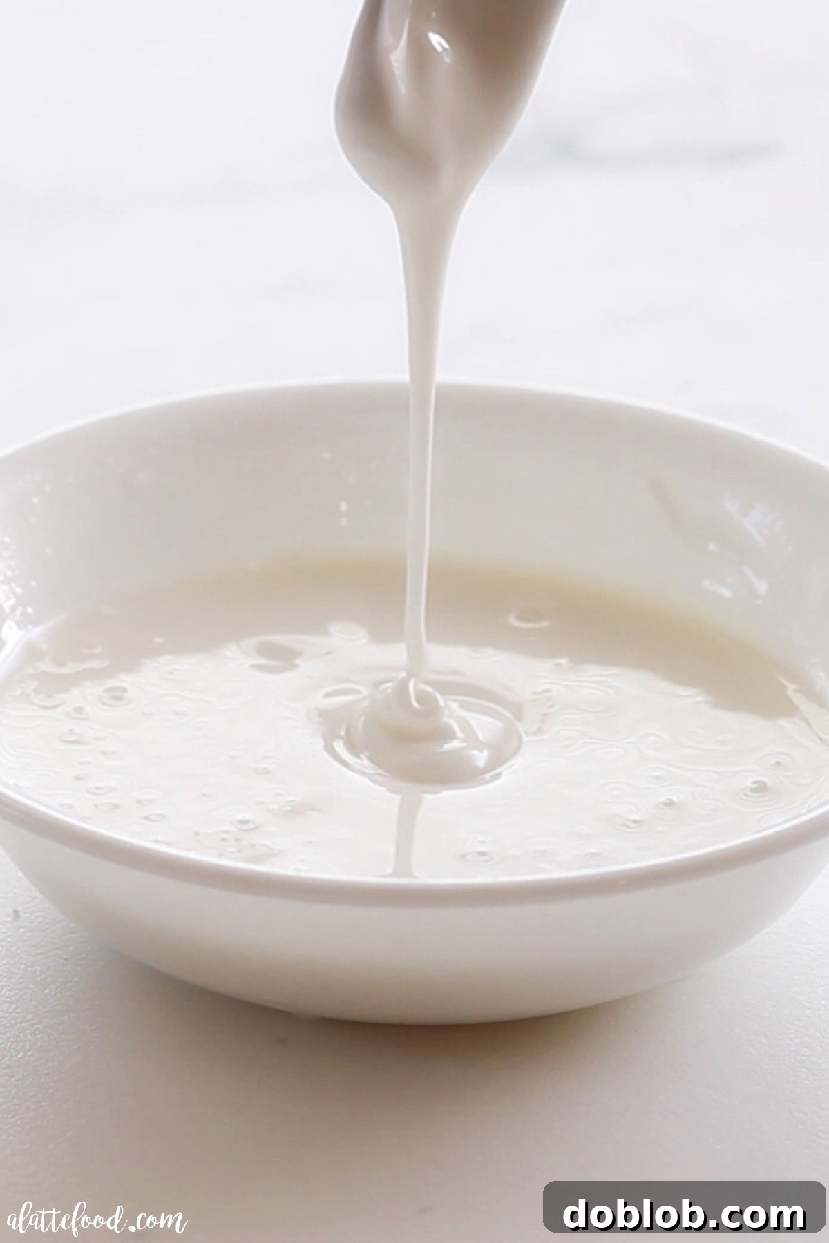 Perfect Royal Icing Made Simple 3 Smooth, thin flooding consistency royal icing dripping off a spoon, ready to fill cookie outlines.