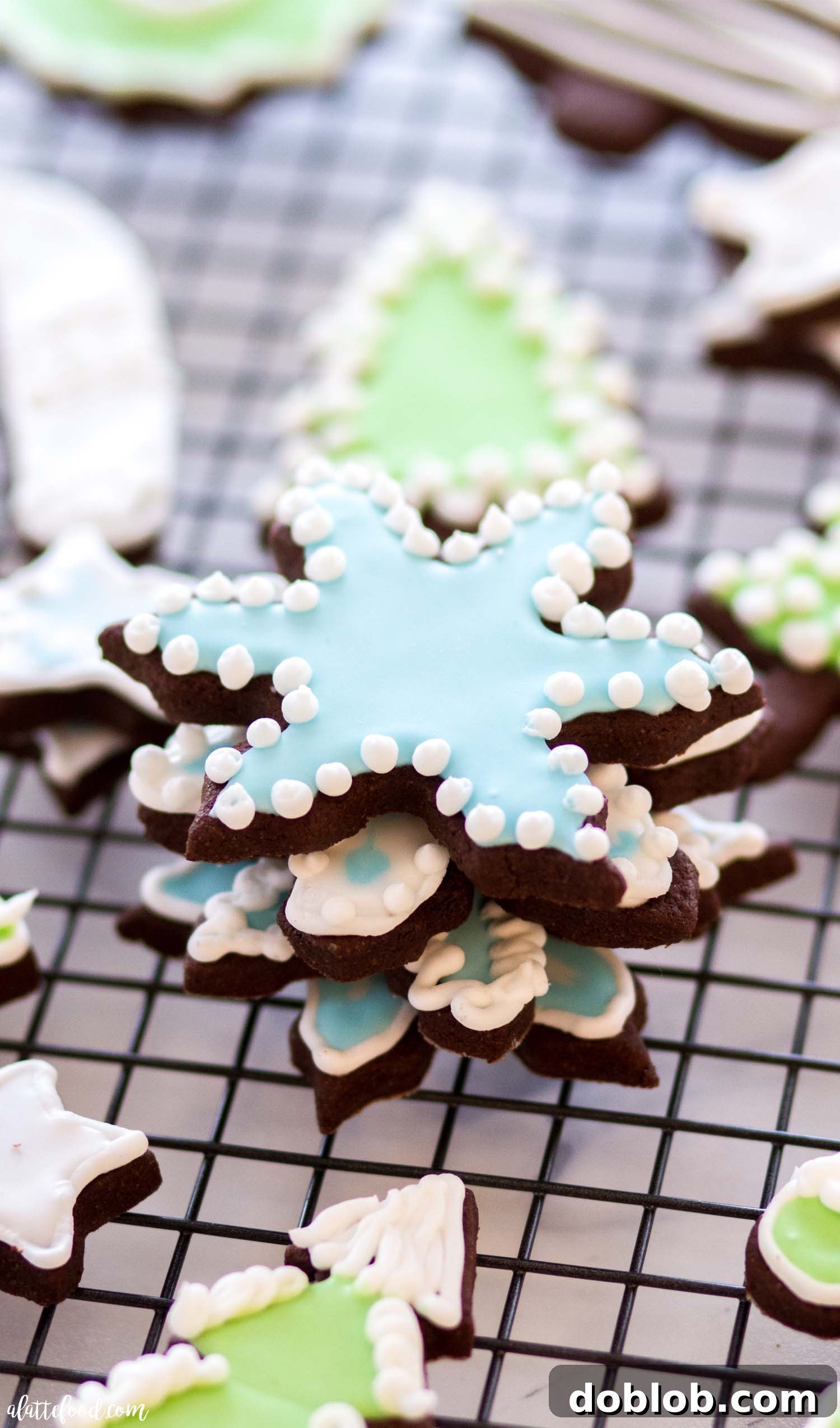 Homemade royal icing is actually so simple! It's made with easy ingredients (made with meringue powder and without egg whites). This recipe has plenty of tips and a video tutorial detailing all the steps for beginners. A collection of delicate snowflake sugar cookies adorned with intricate white royal icing designs, neatly stacked.