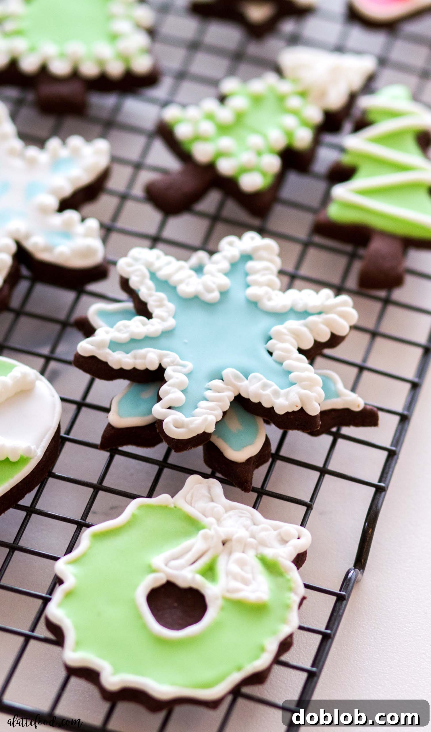 This easy royal icing recipe is made without egg whites and corn syrup, and instead uses meringue powder. Learn how to make royal icing perfect every single time with all the tips and tricks I've learned. From piping to flooding to wet on wet techniques, you can't mess up this recipe. Plus, a video. Various royal icing sugar cookies, beautifully decorated and stacked on a cooling rack, showcasing diverse designs.