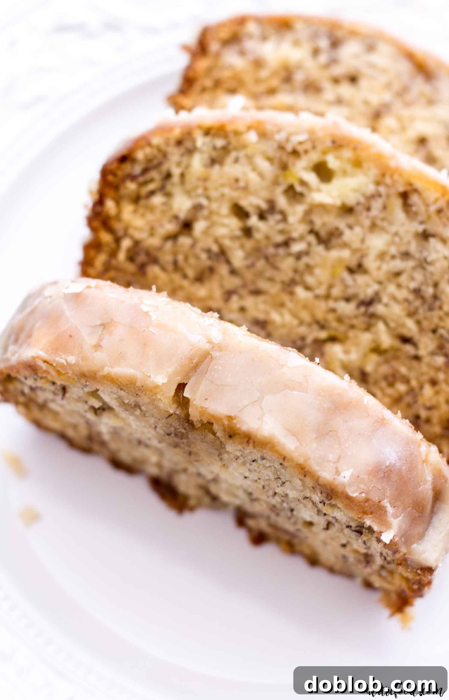 Glazed Banana Bread is one of my favorite things of all time! This is a classic banana bread that’s super moist (without sour cream!) and so flavorful. The maple glaze is the perfect addition to this fall dessert staple. glazed banana bread slice on white plate