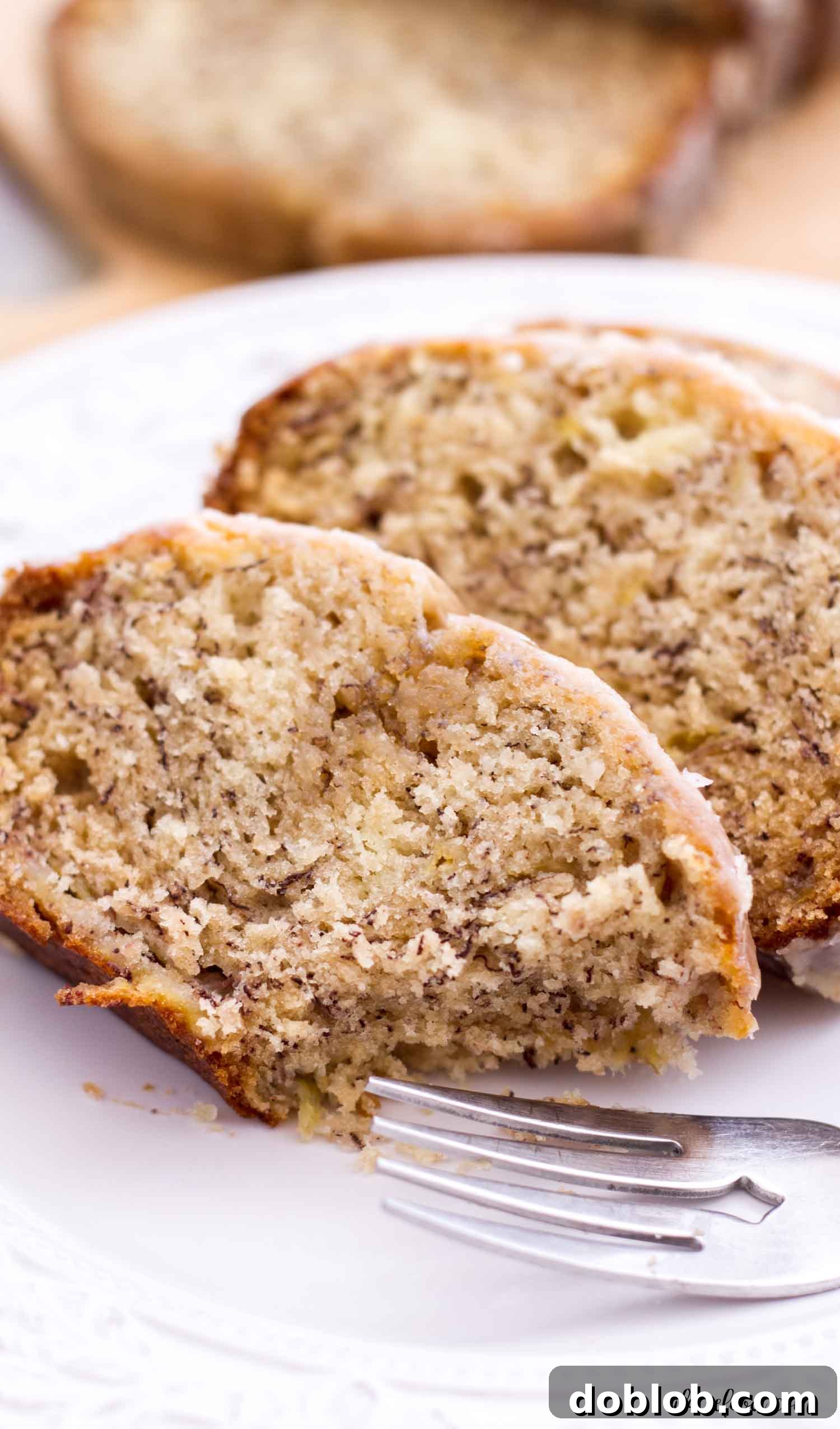 Classic banana bread is given a fall twist with a maple glaze drizzled on top. This moist banana bread (made without sour cream!) is so easy to make, and it makes one of the absolute best fall recipes! slice of banana bread with bite missing on plate