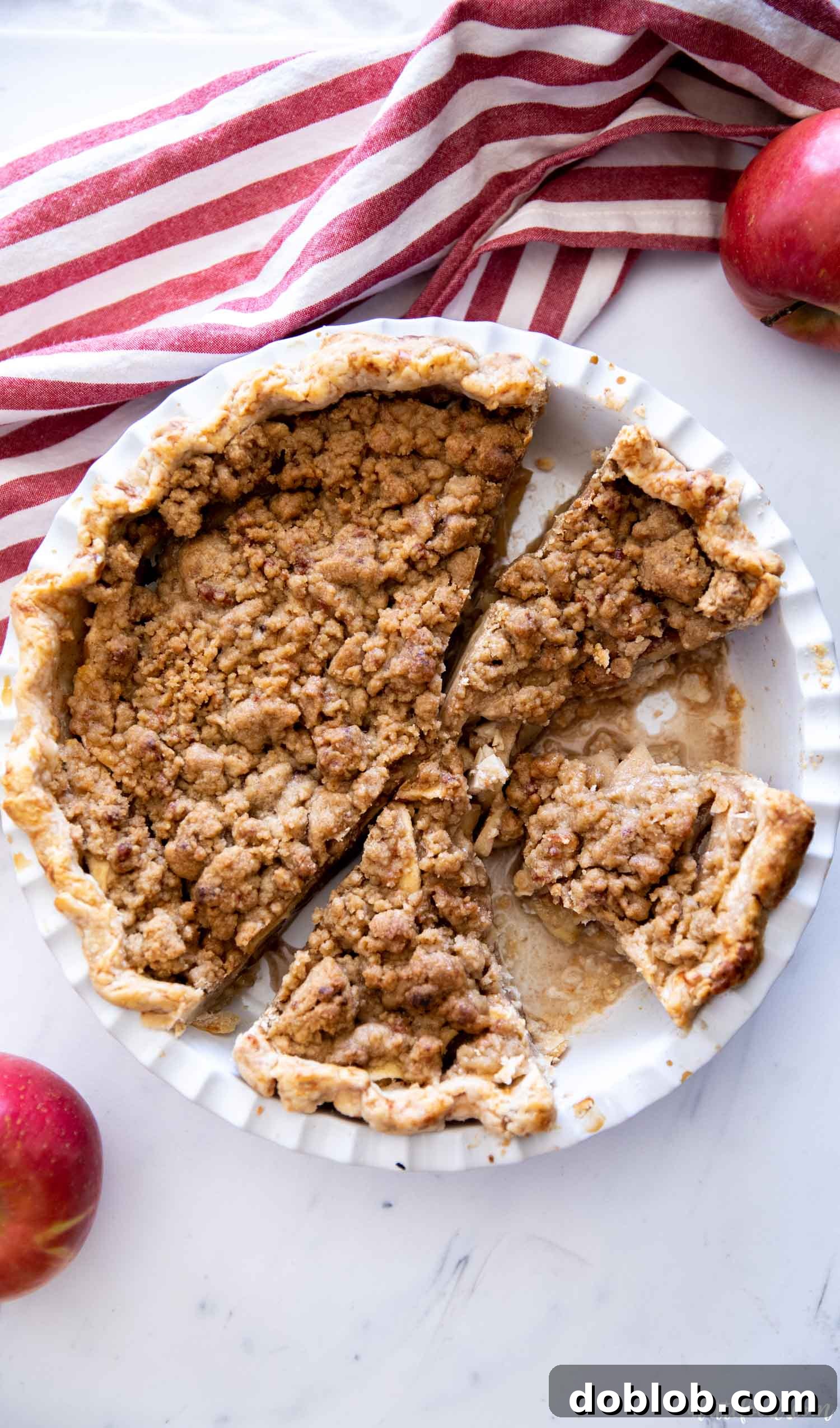 baked apple crumb pie in white pie plate on marble board