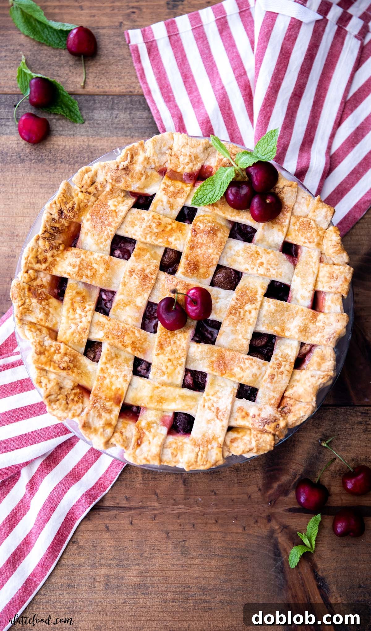 A whole homemade cherry pie with a rustic lattice crust, sitting on a wooden counter, highlighting its fresh, ready-to-serve appearance.