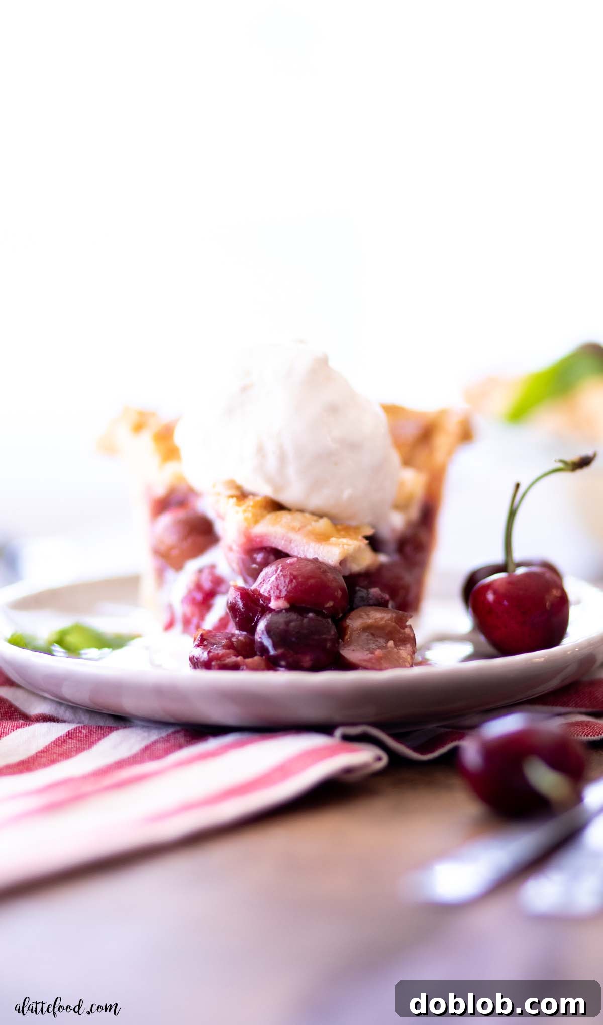 A close-up of a slice of homemade cherry pie with ice cream, showcasing the flaky crust and rich filling.
