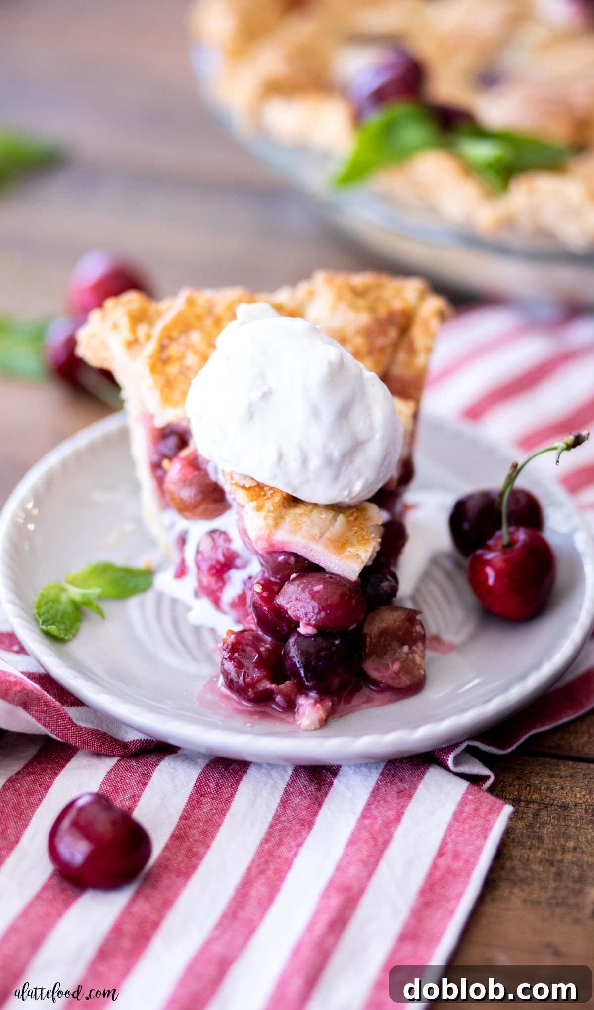A slice of cherry pie à la mode on a gray plate, showcasing the rich filling and flaky crust.
