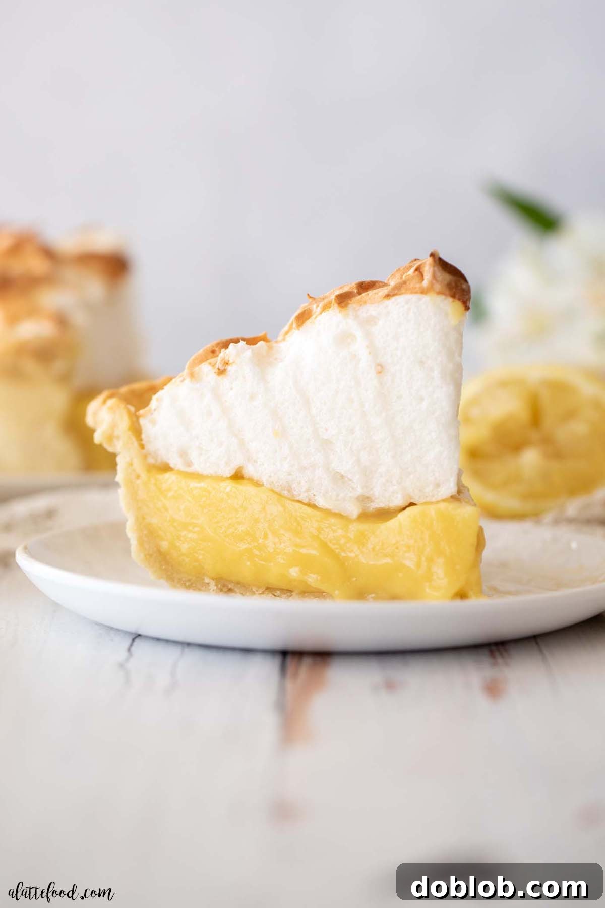 Slice of homemade lemon meringue pie on a white plate, showcasing its layers.