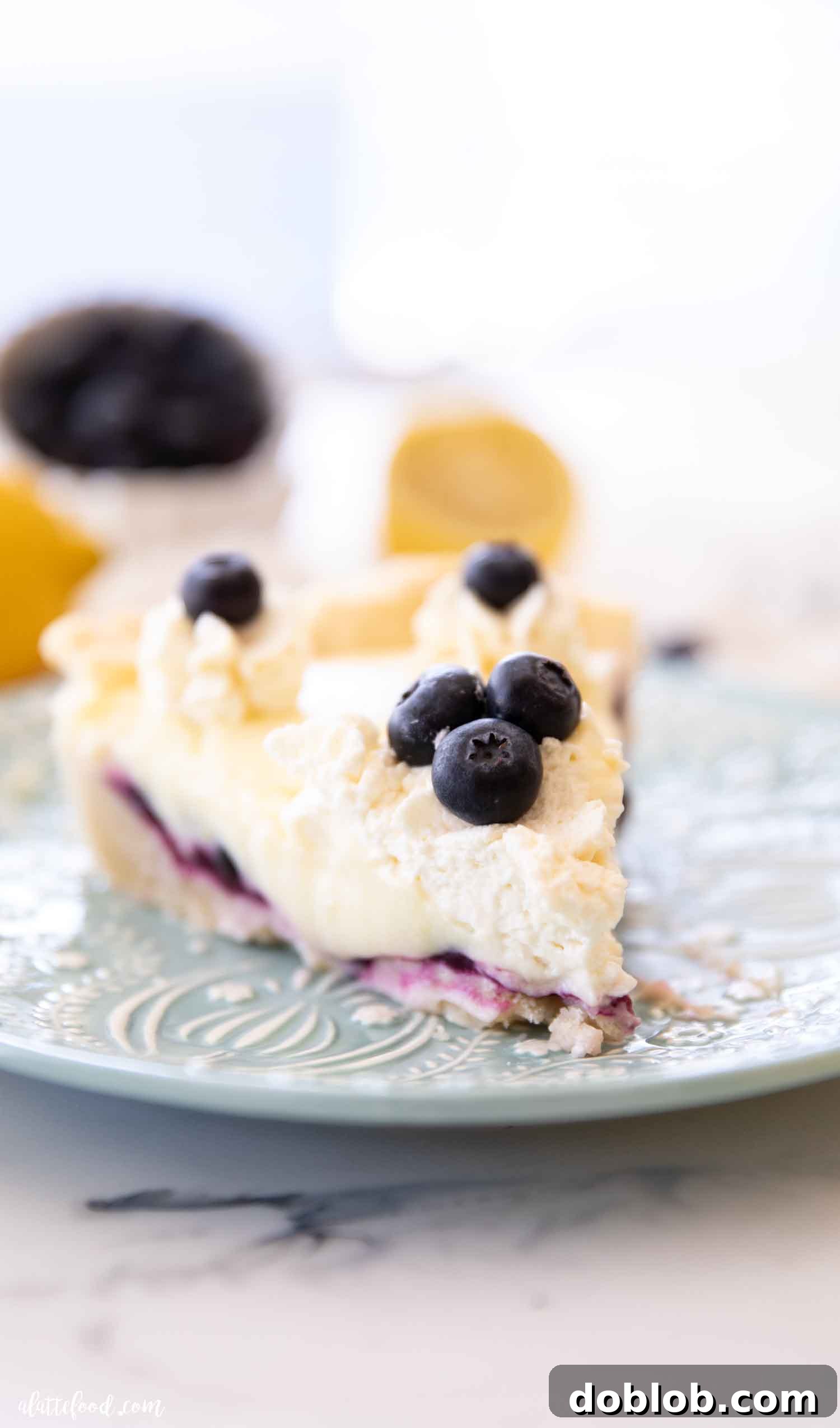 Blueberry lemon cream pie slice on a blue plate, showing layers of shortbread crust, blueberry filling, and lemon custard.