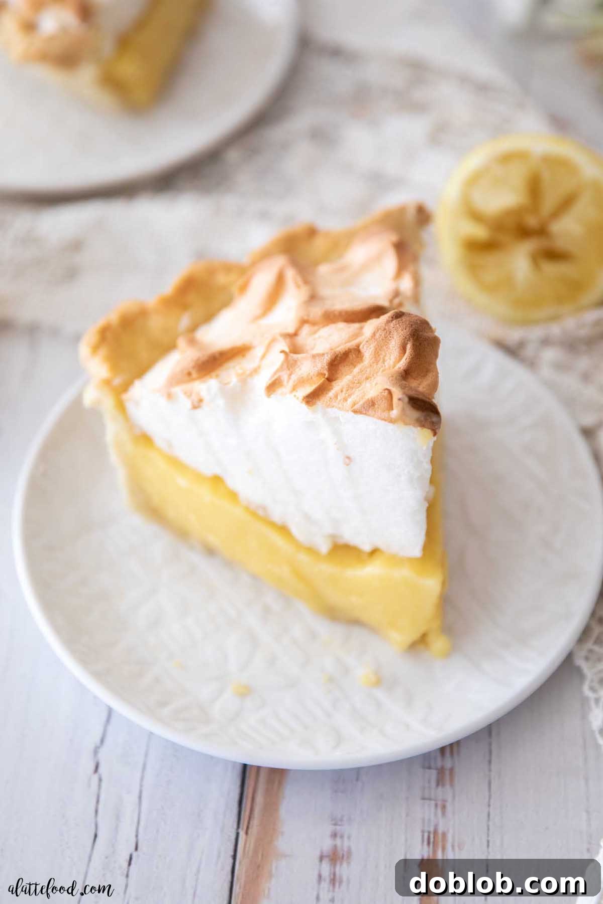 A slice of perfectly toasted lemon meringue pie on a white plate, highlighting its rich filling and fluffy meringue.