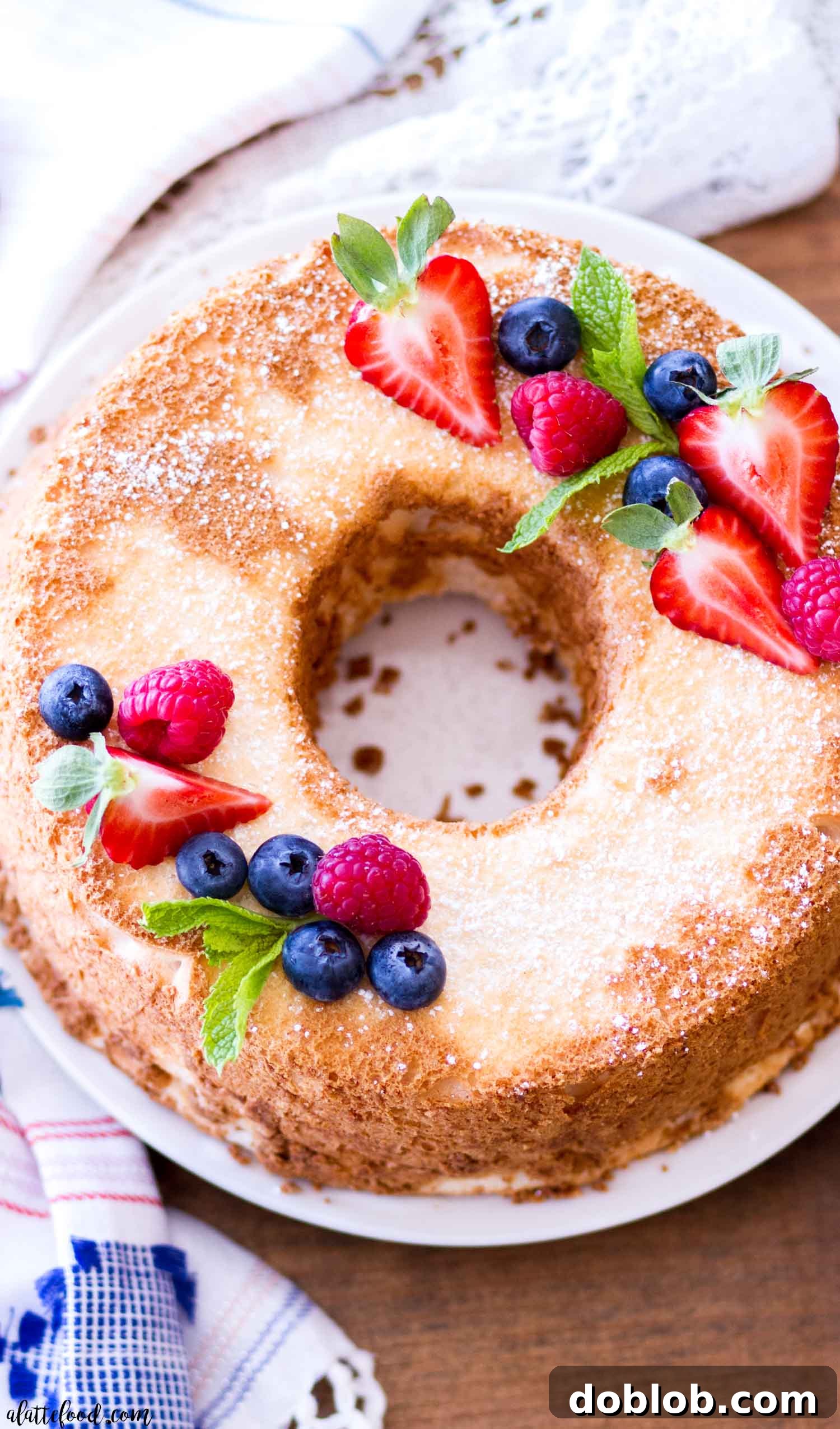 A light and airy angel food cake, dusted with powdered sugar and served on a white plate.