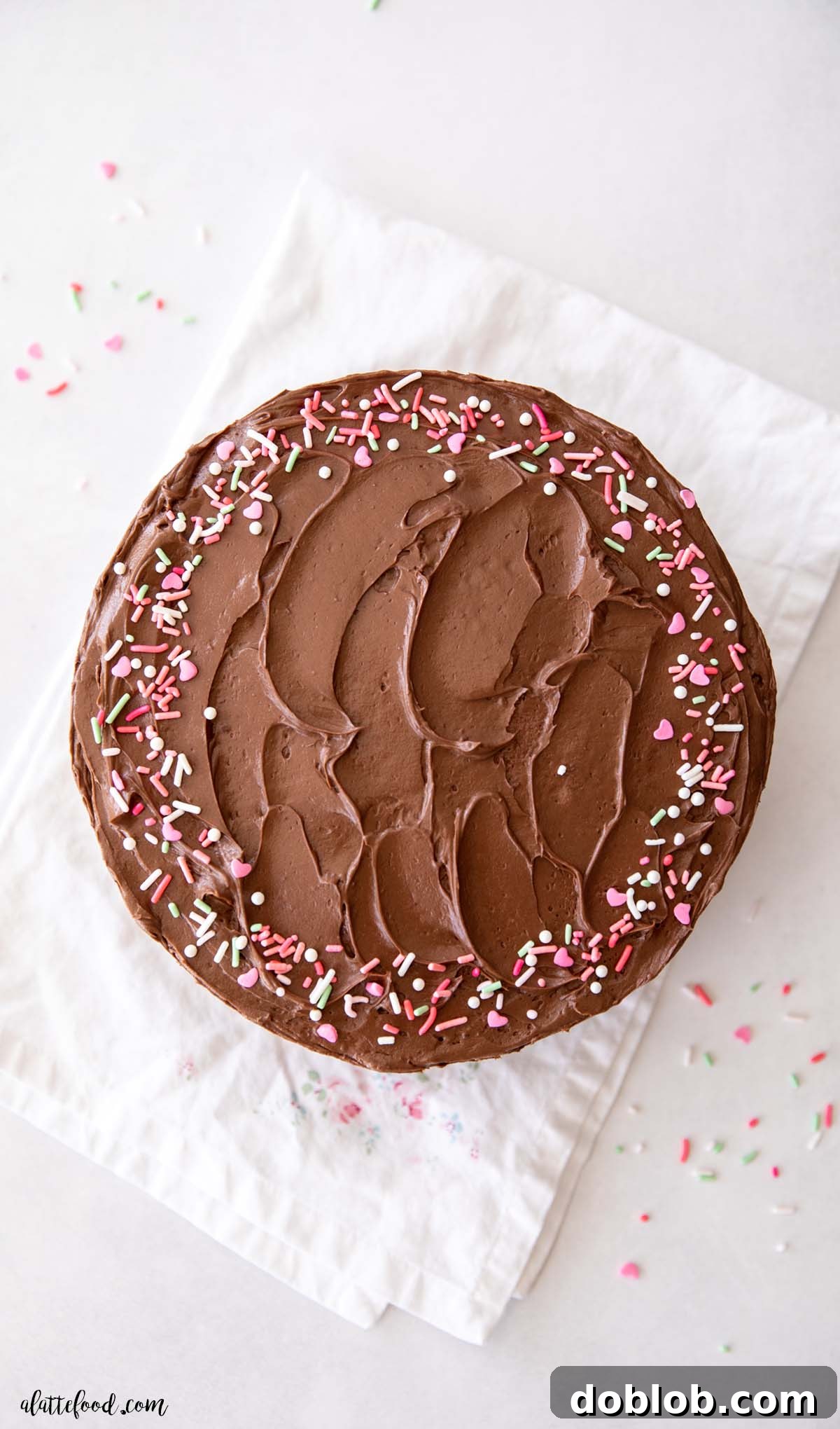 A beautifully frosted yellow cake, generously covered in creamy chocolate buttercream and playful sprinkles, ready for any celebration.