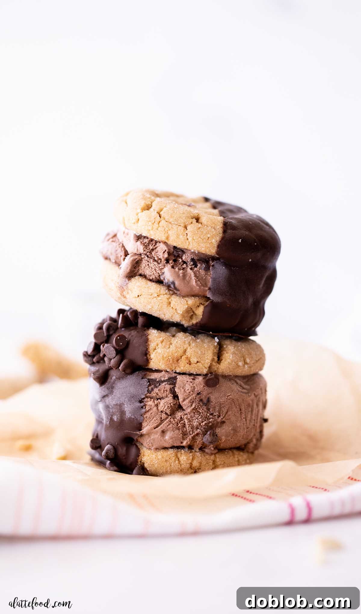 Two chocolate peanut butter ice cream sandwiches stacked on top of each other, showcasing their layers