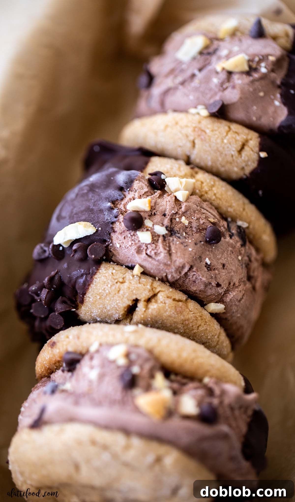 Chocolate peanut butter cookie ice cream sandwiches laying on their sides in a parchment-lined box