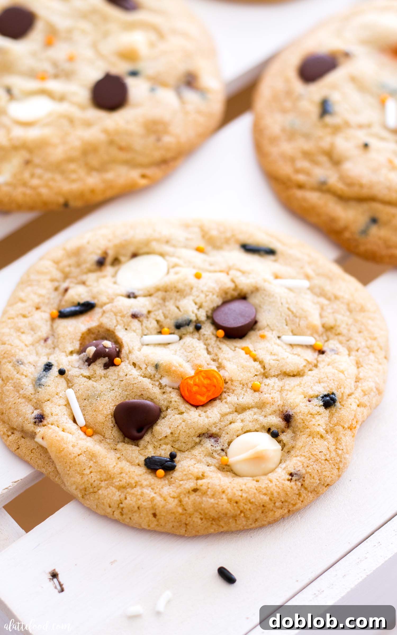 A single hand reaching for a warm, freshly baked Cake Batter Funfetti Chocolate Chip Cookie