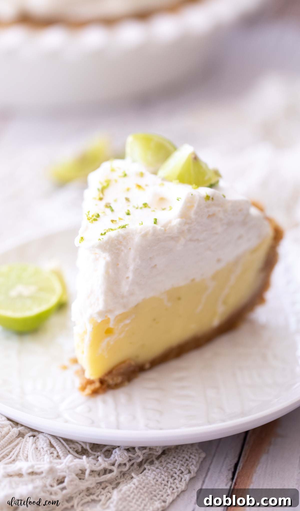 slice of key lime cream pie on a white plate with fresh key limes