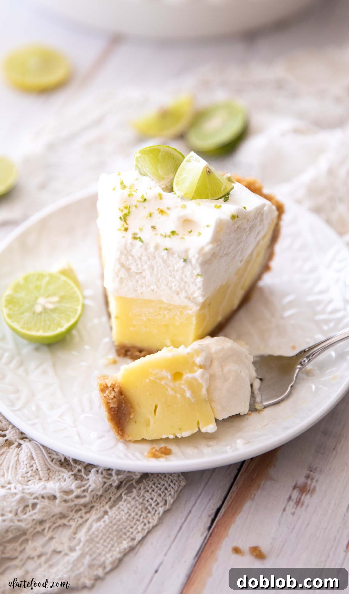 slice of key lime pie with a bite on a fork on a white plate 