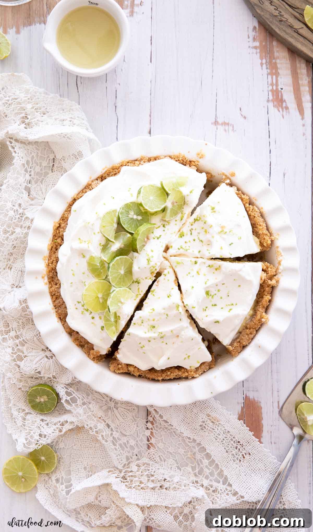 key lime custard pie with whipped cream cut in slices in a white pie plate