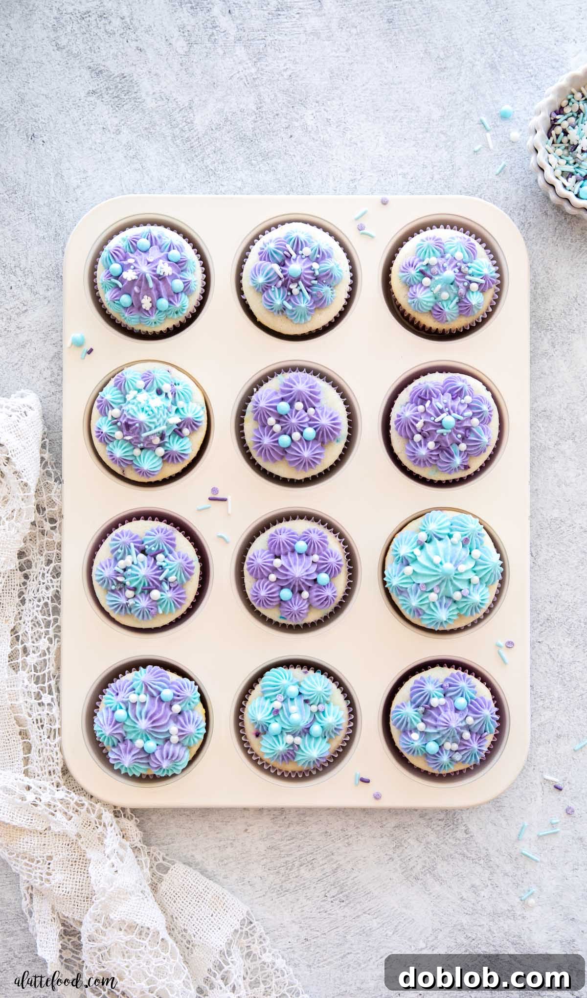 A tray of freshly baked homemade Funfetti cupcakes with creamy vanilla frosting, elegantly arranged in a white muffin tin, showcasing their delightful appearance.