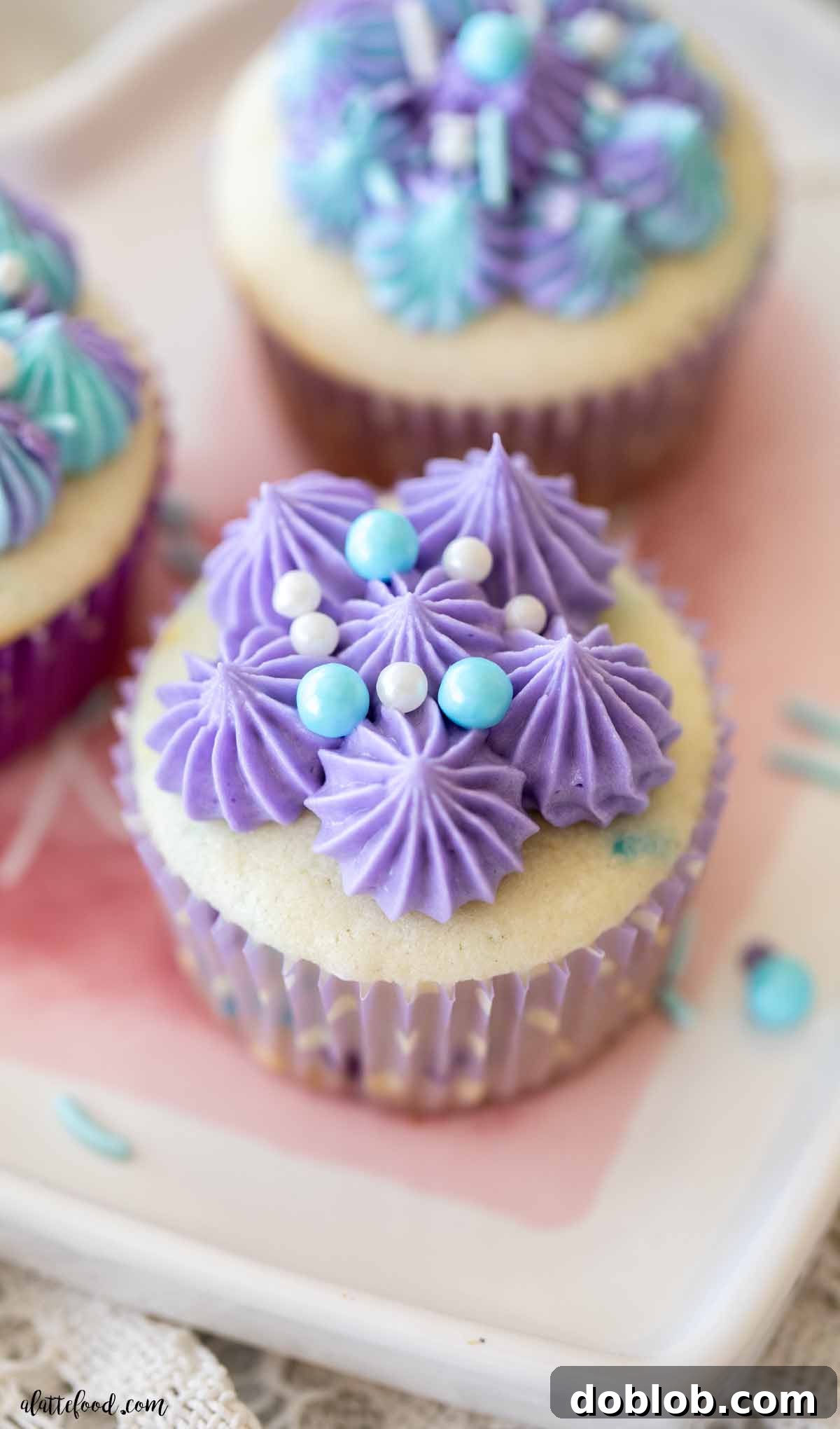 A single baked Funfetti cupcake, also known as confetti cupcake, beautifully adorned with vibrant purple frosting and a delicate scattering of blue and white sprinkles, ready for a taste test.