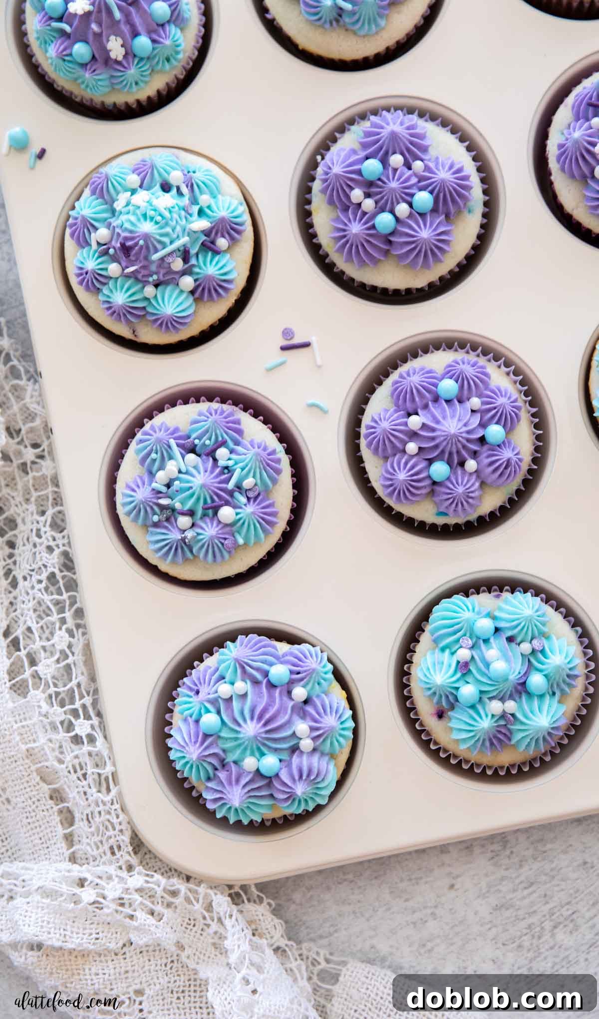 A trio of vanilla-frosted Funfetti cupcakes beautifully arranged in a white muffin tin, adorned with a scattering of colorful sprinkles, ready to be served.