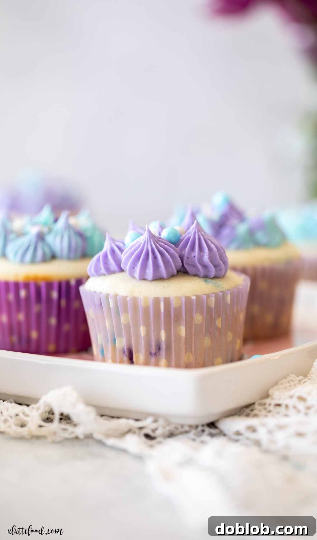 Fluffy white Funfetti cupcakes with creamy vanilla frosting beautifully arranged on a white plate, showcasing their inviting texture.