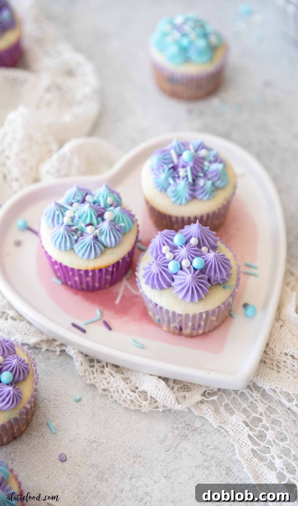 A plate of fluffy homemade Funfetti cupcakes from scratch, showcasing their vibrant sprinkles and inviting texture on a white heart-shaped plate.
