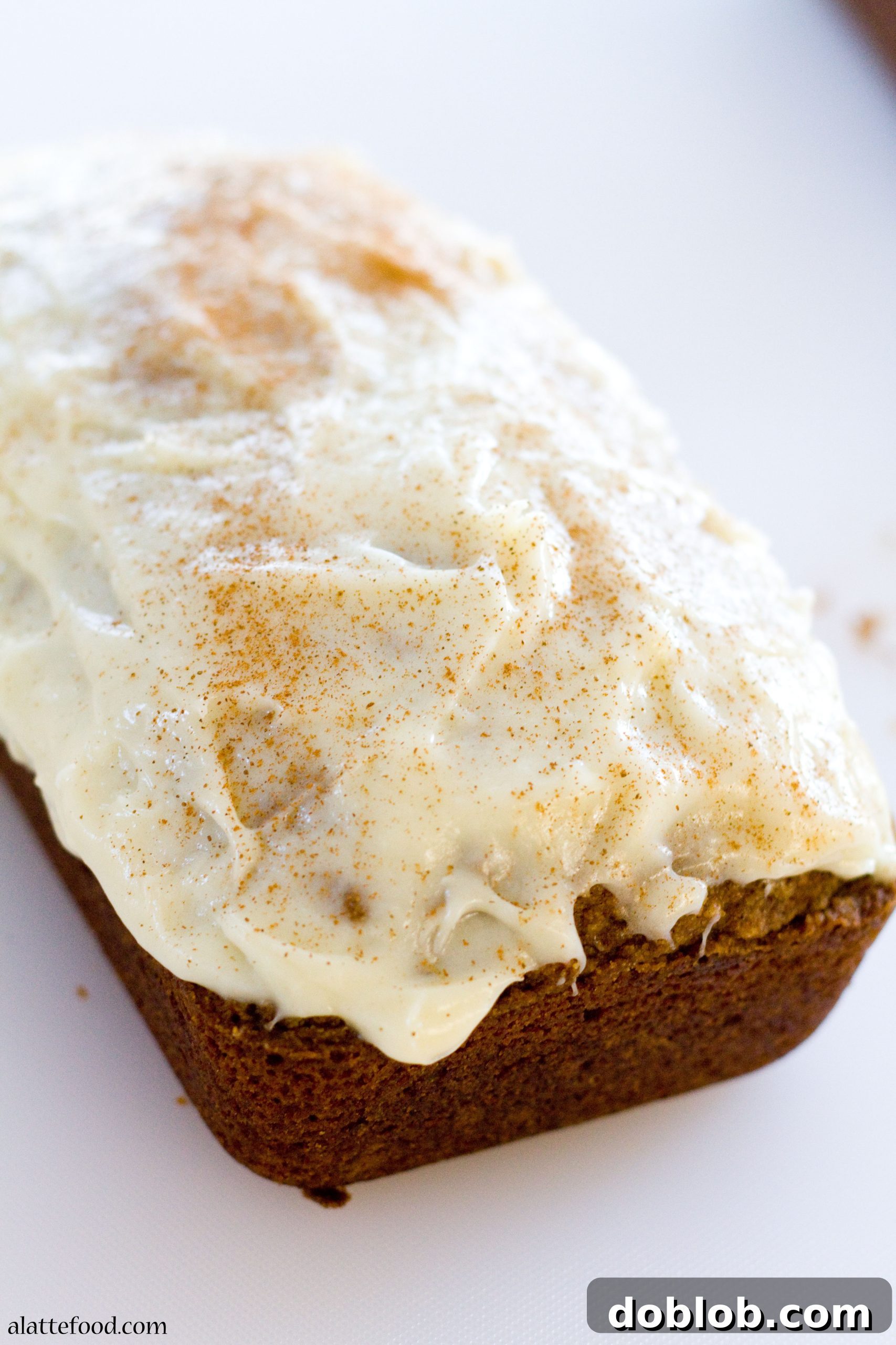Two loaves of Classic Pumpkin Streusel Bread, one with a cream cheese glaze drizzle.