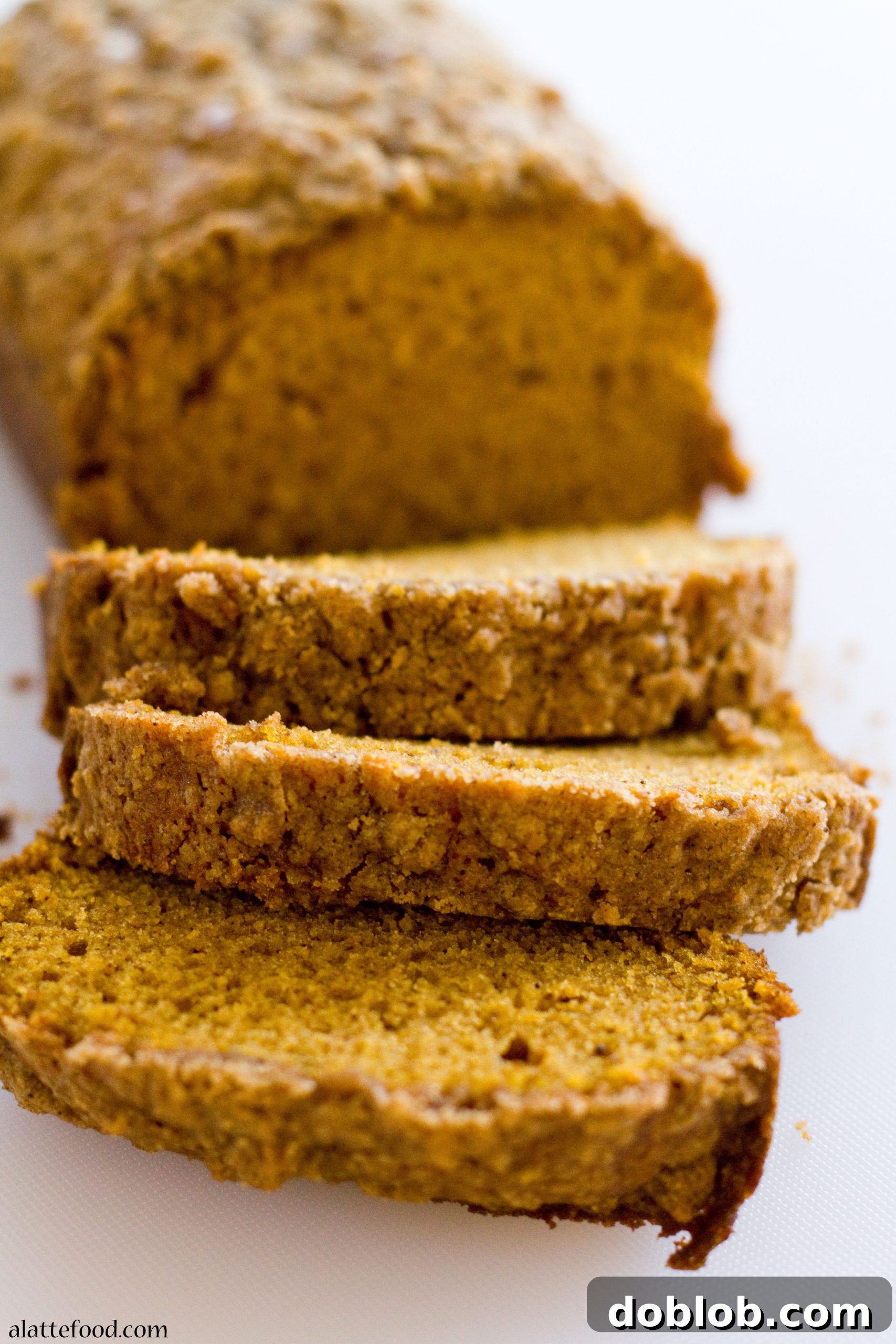 The golden-brown, crunchy streusel topping on a baked loaf of pumpkin bread.