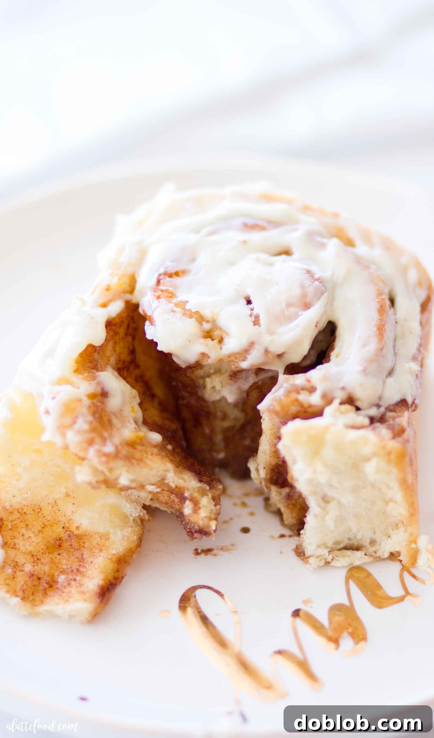 soft cinnamon roll with gooey filling on white and gold plate
