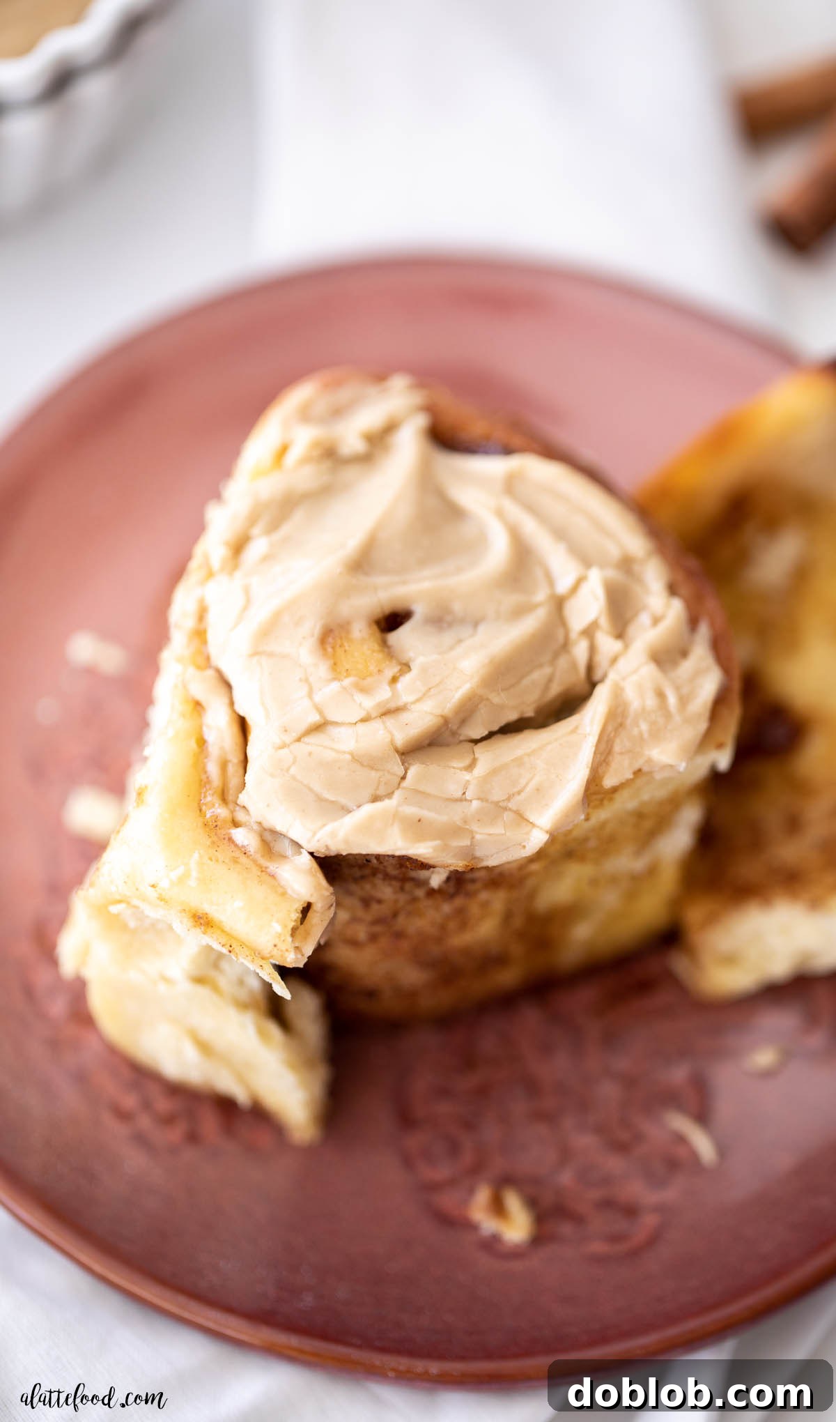 brown sugar frosted cinnamon rolls with pumpkin butter on maroon plate