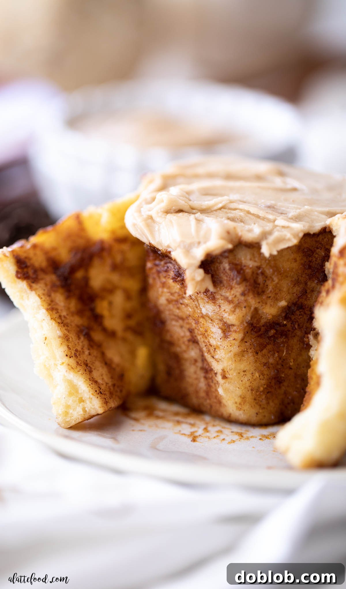 pumpkin butter cinnamon roll with brown sugar frosting on white plate