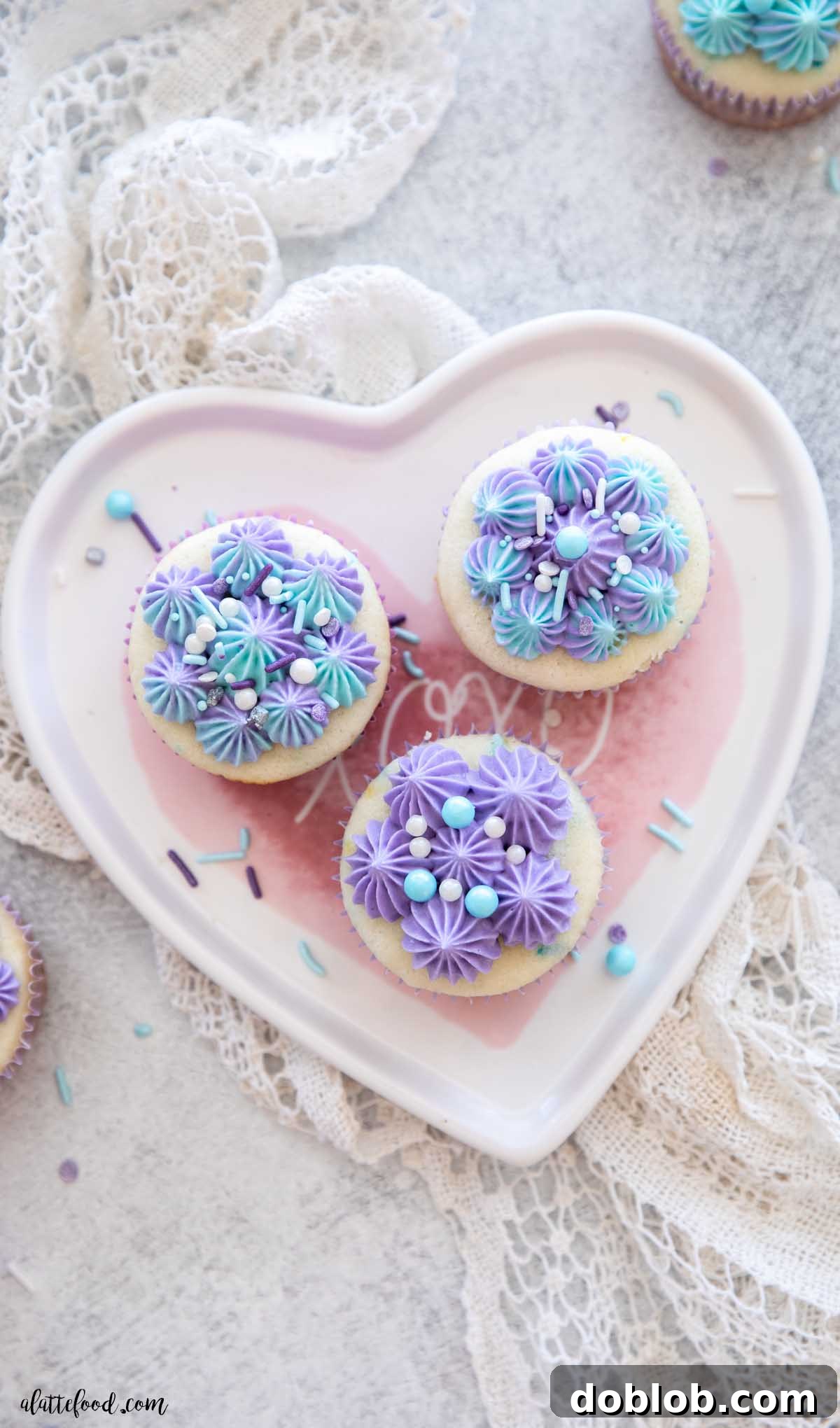 three confetti cupcakes with vanilla buttercream on a heart shaped plate