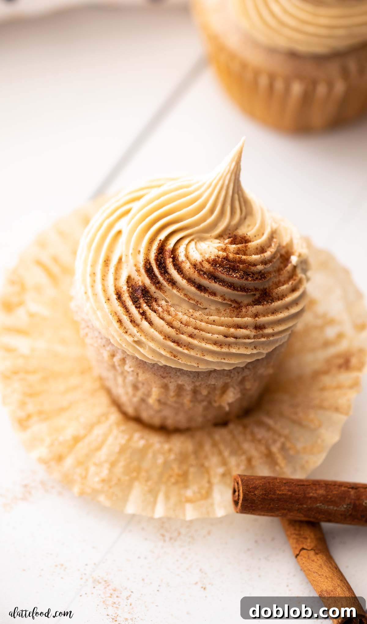 brown sugar frosted snickerdoodle cupcake with cinnamon sticks on white board