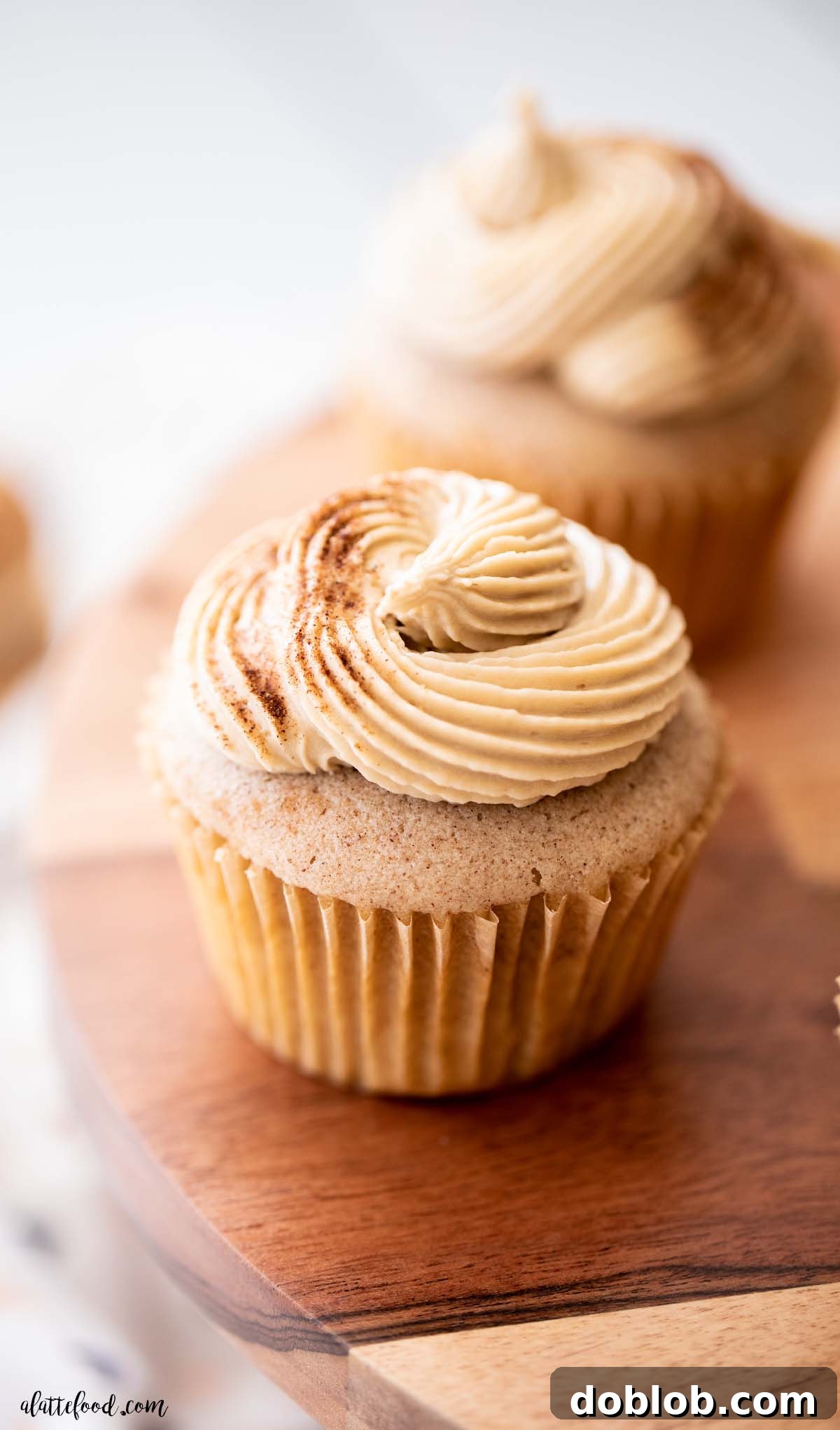 cinnamon cupcakes on wood cake plate with swirled frosting