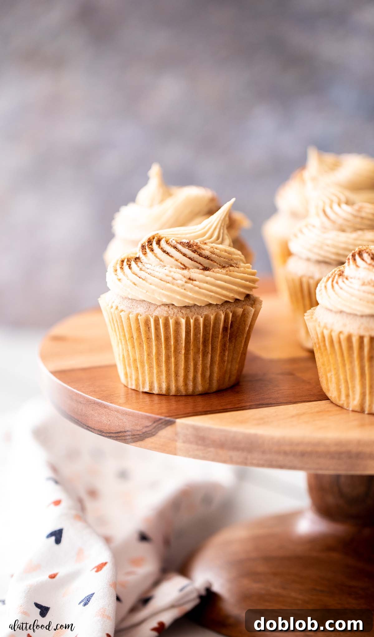 brown sugar frosted snickerdoodle cupcakes on wood cake stand