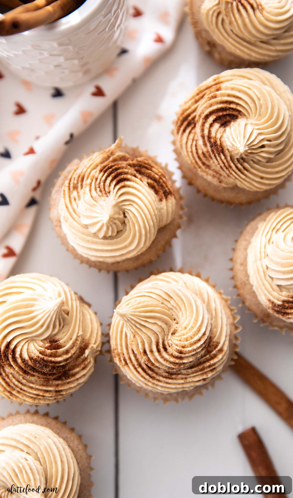 frosted cinnamon cupcakes with cinnamon sticks on white board